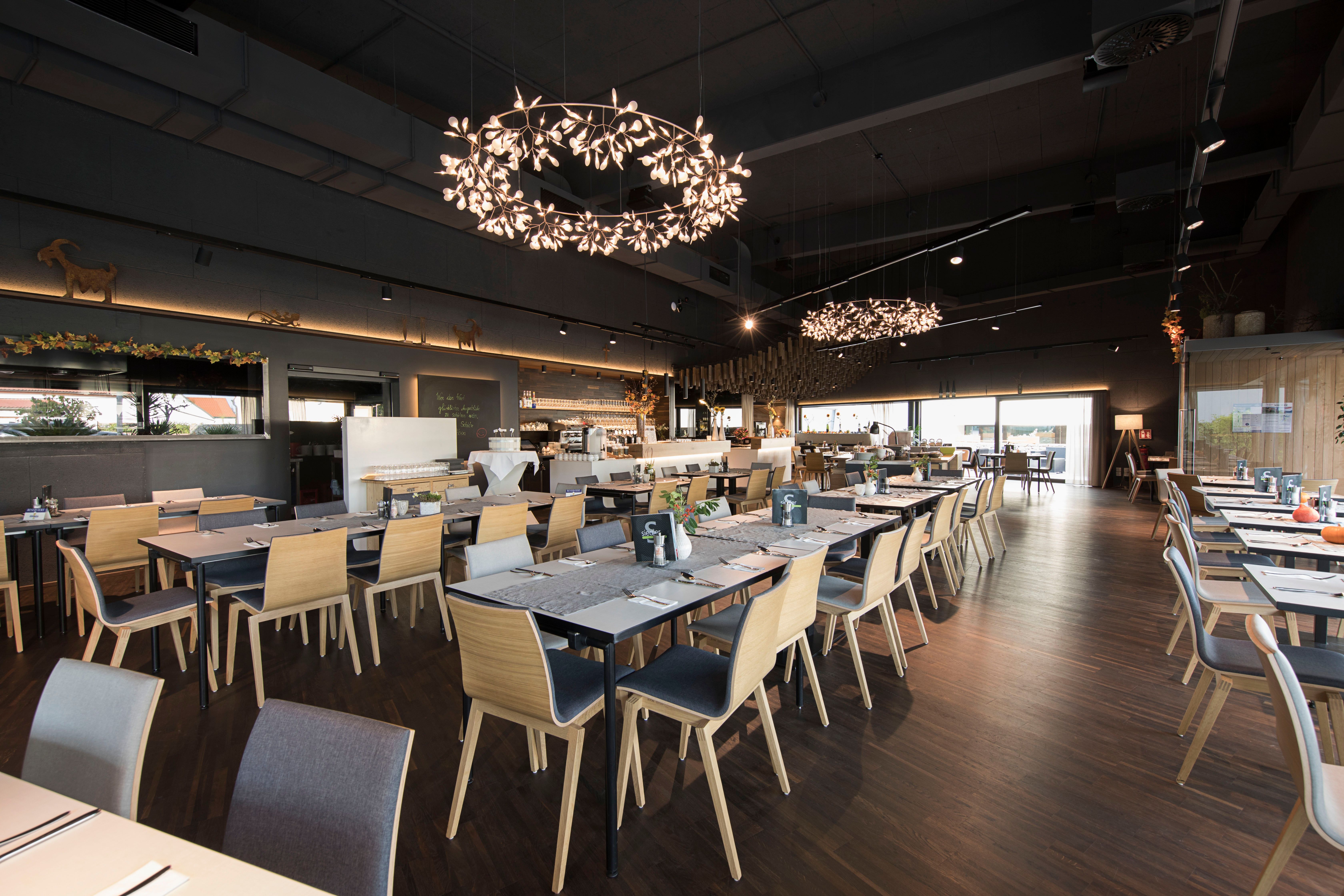 Modernes Restaurant mit Holzstühlen und dekorativen Kronleuchtern.