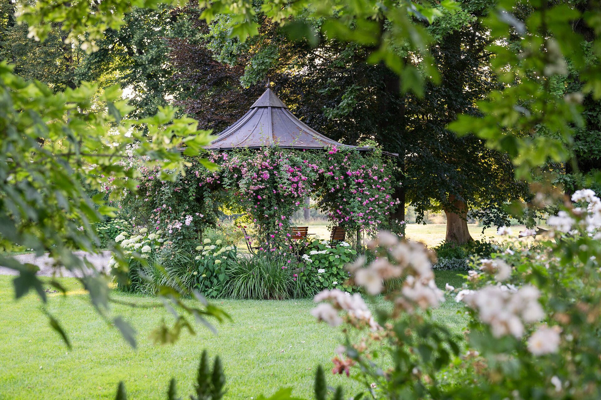 Top Ausflugsziel GARTEN TULLN. Überwachsener Bogen zum Durchgehen führt entlang des Weges. Viele grüne Büsche im Hintergrund, strahlend blauer Himmel und Sonnenschein.