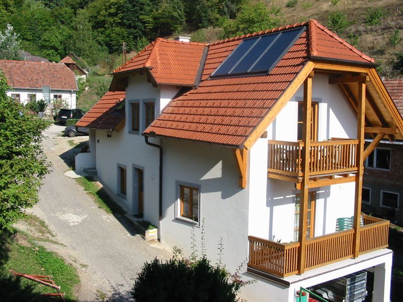 Vacation apartment with red roof and solar panels in a rural setting.