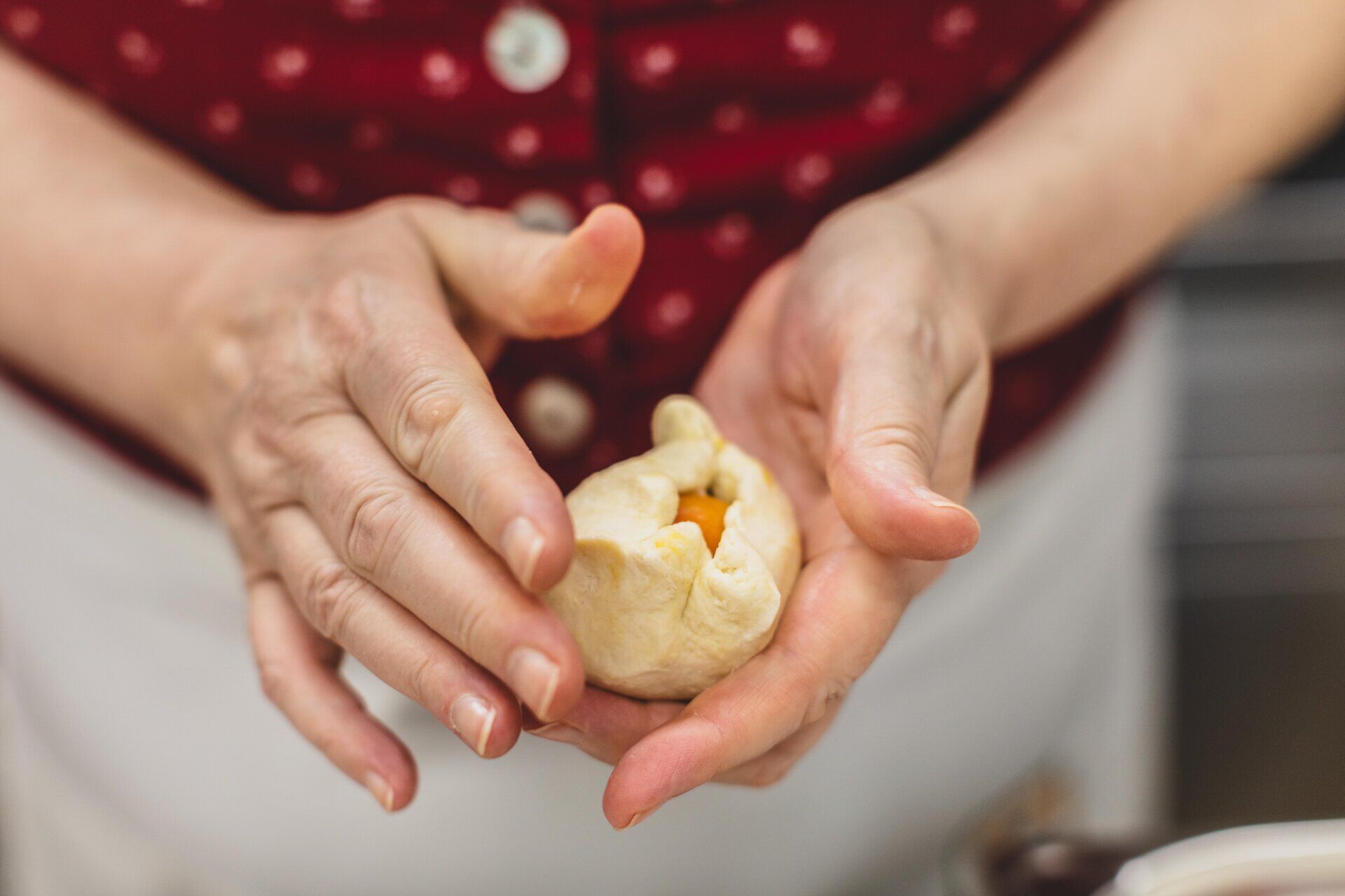In der warmen Sommerluft werden köstliche Marillenknödel zubereitet, die mit frischen, saftigen Aprikosen gefüllt sind. Die Hände formen liebevoll den Teig, während der Duft von frischem Obst die Sinne verführt. Ein Genuss, der die Tradition der Wachauer Spezialitäten lebendig hält.