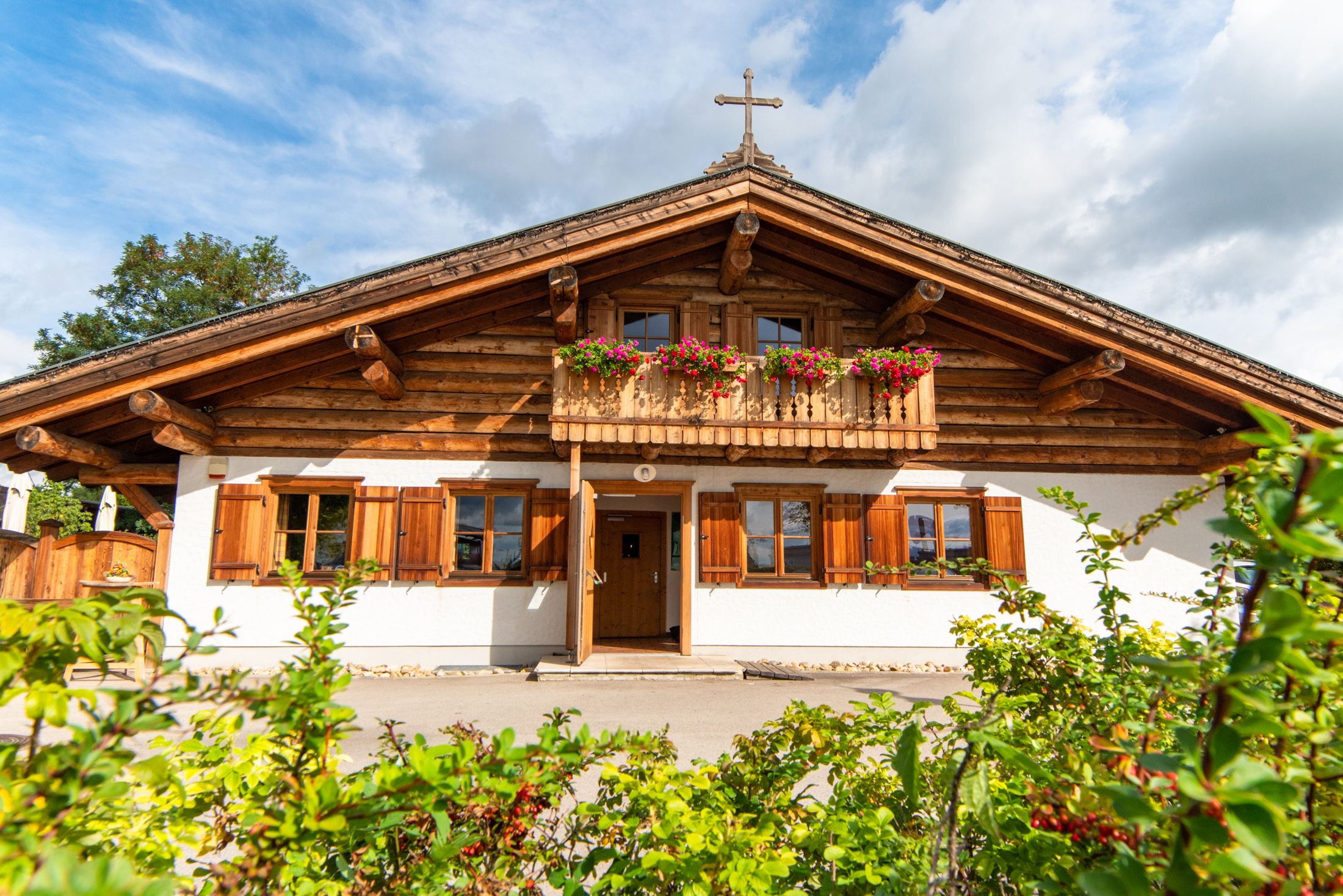 Traditionelles Holzhaus mit Balkon und Blumenkästen, blauer Himmel im Hintergrund.