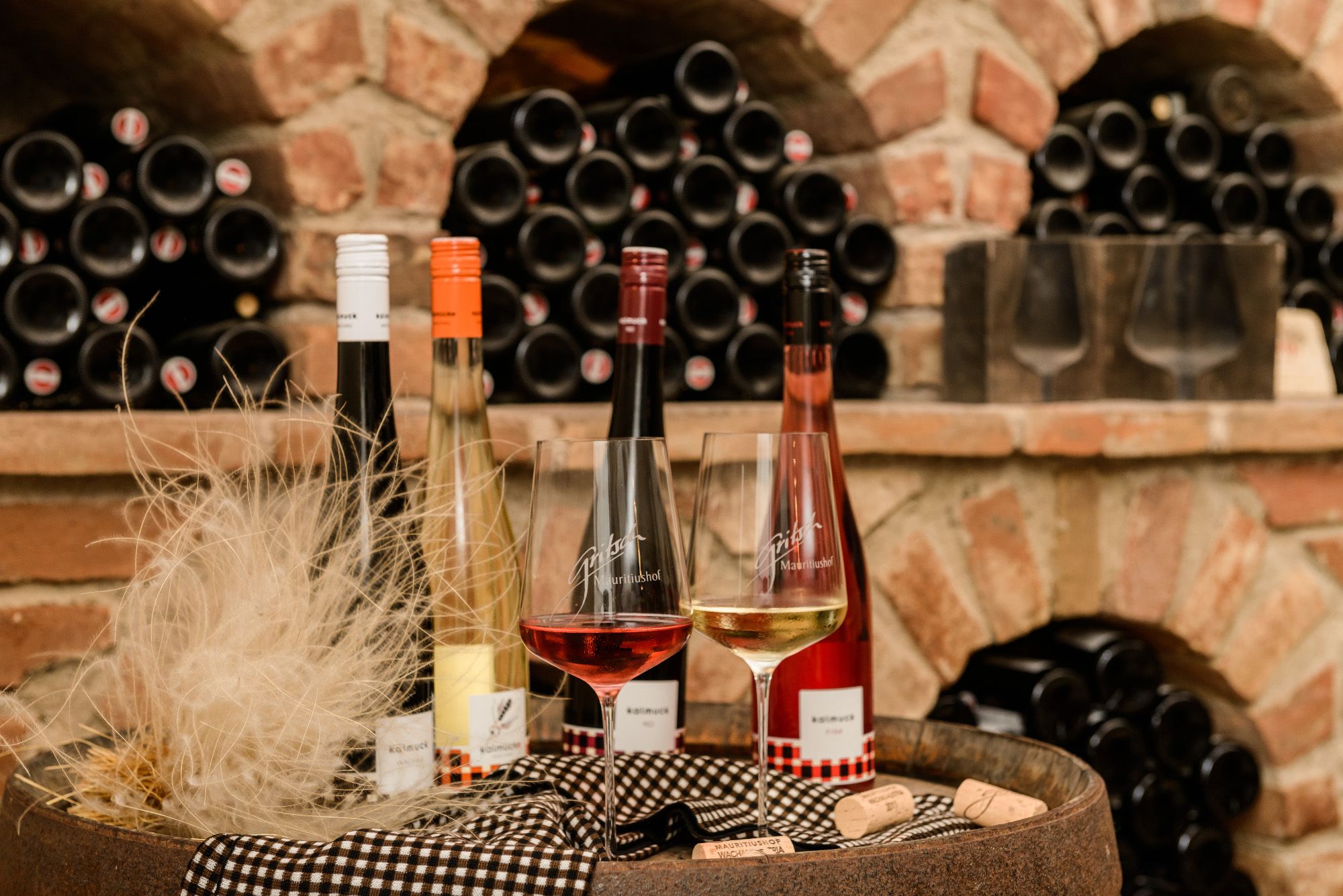 Weinflaschen und Gläser vor einem Regal mit Weinflaschen in einem Weinkeller.