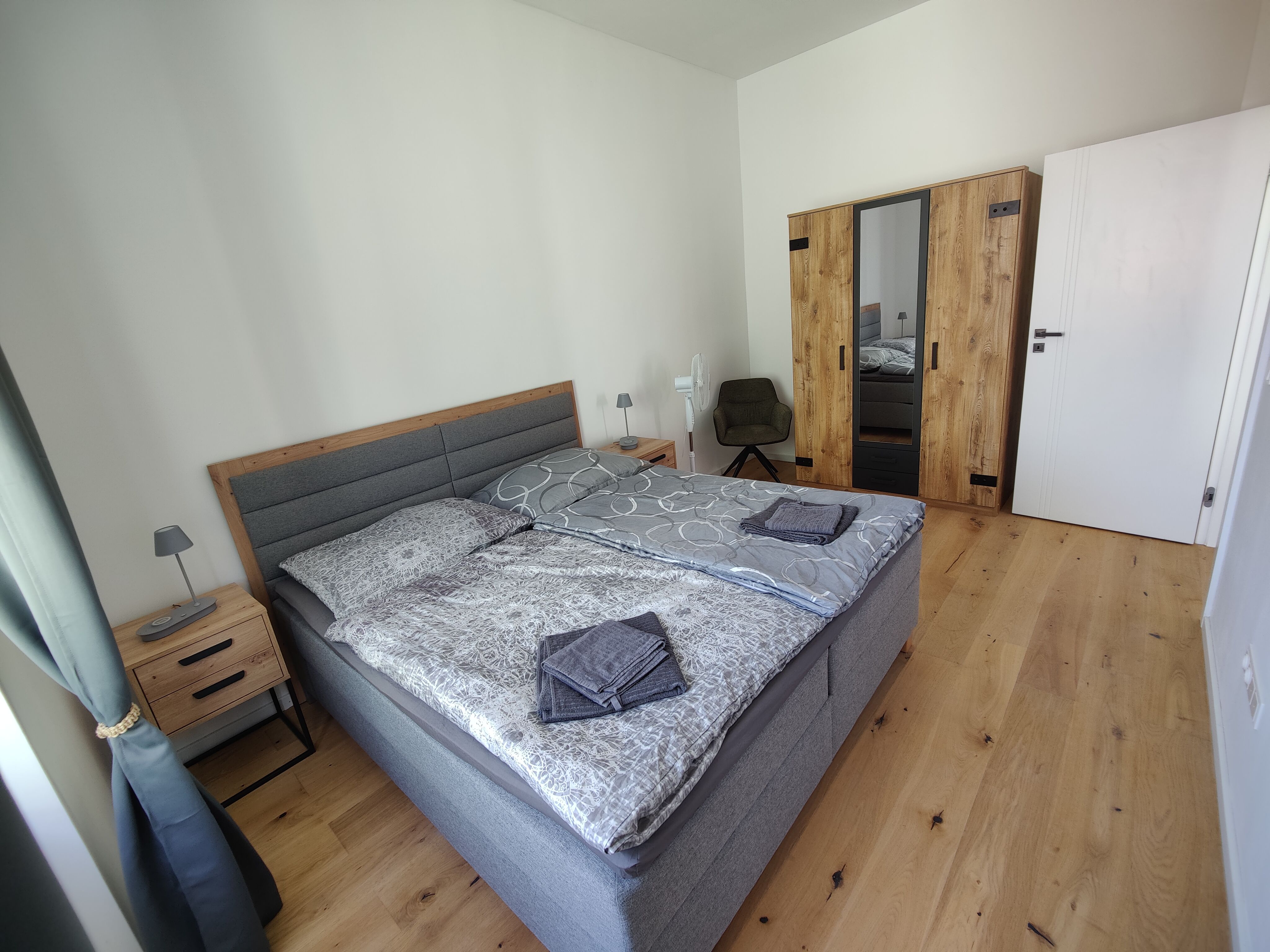 Schlafzimmer Apartment Felicitas mit Holzfussboden und grauem Boxspringbett