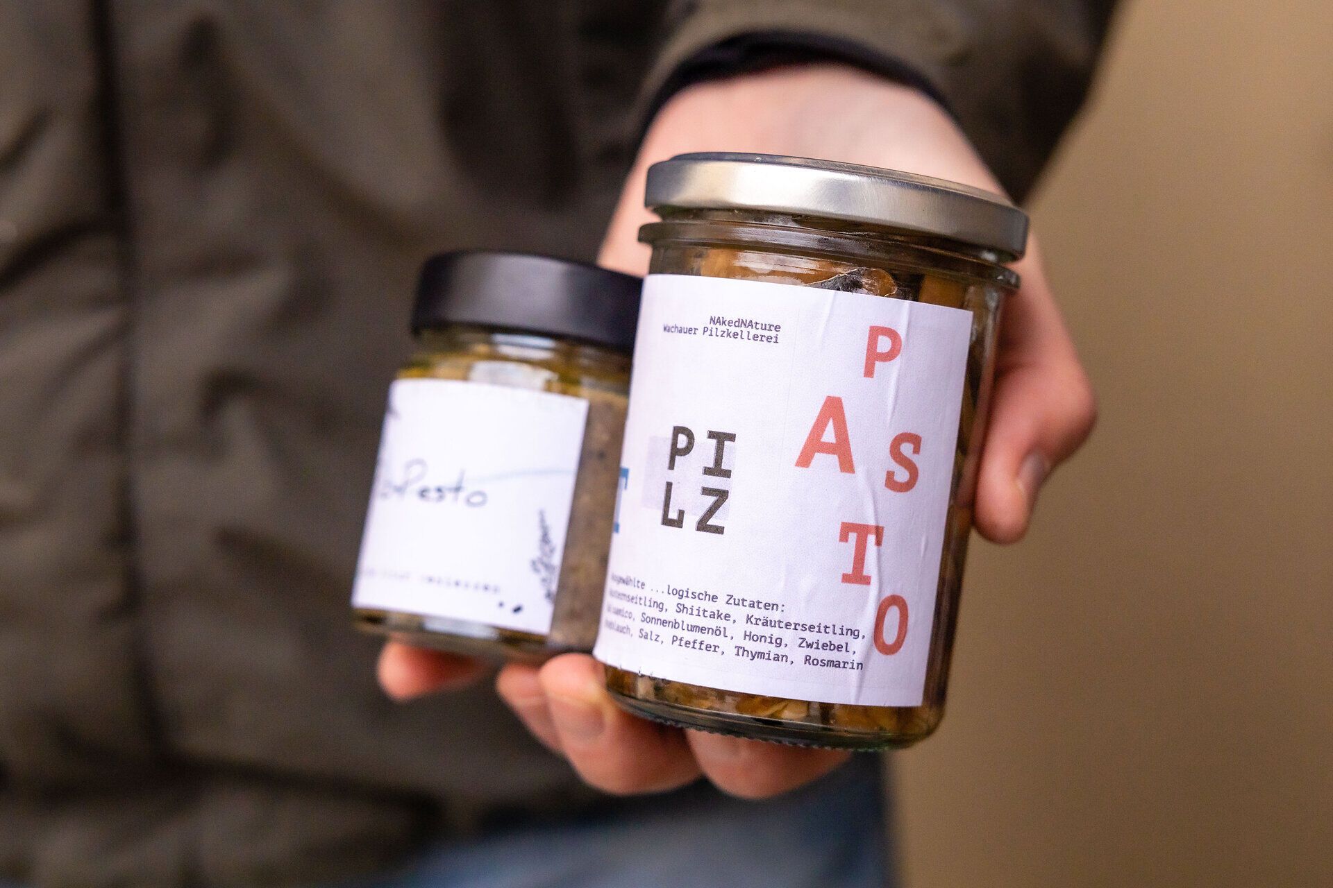 Eine Hand hat zwei Gläser mit Pasta in der Hand.