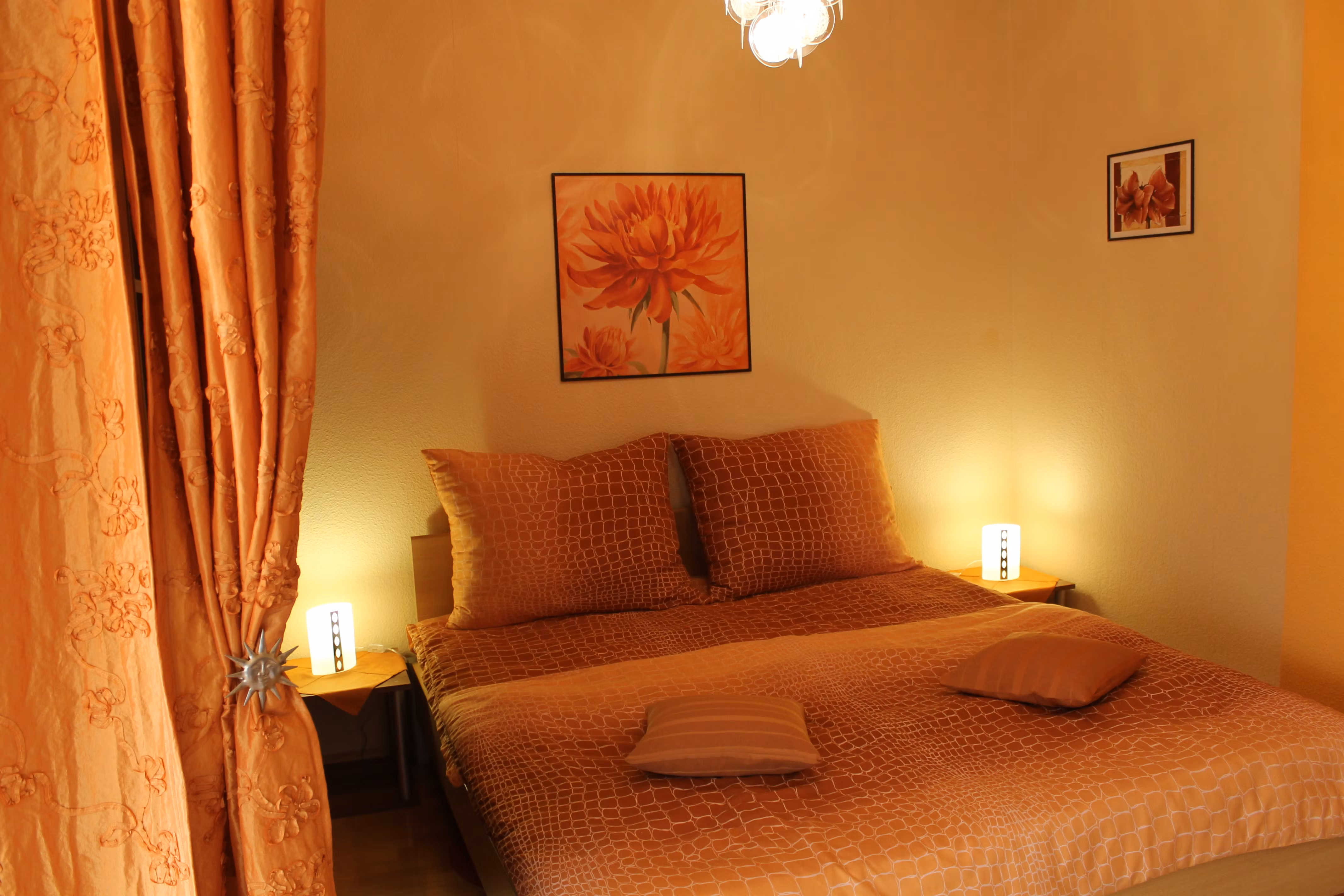 A cozy bedroom with orange decoration and lighting.