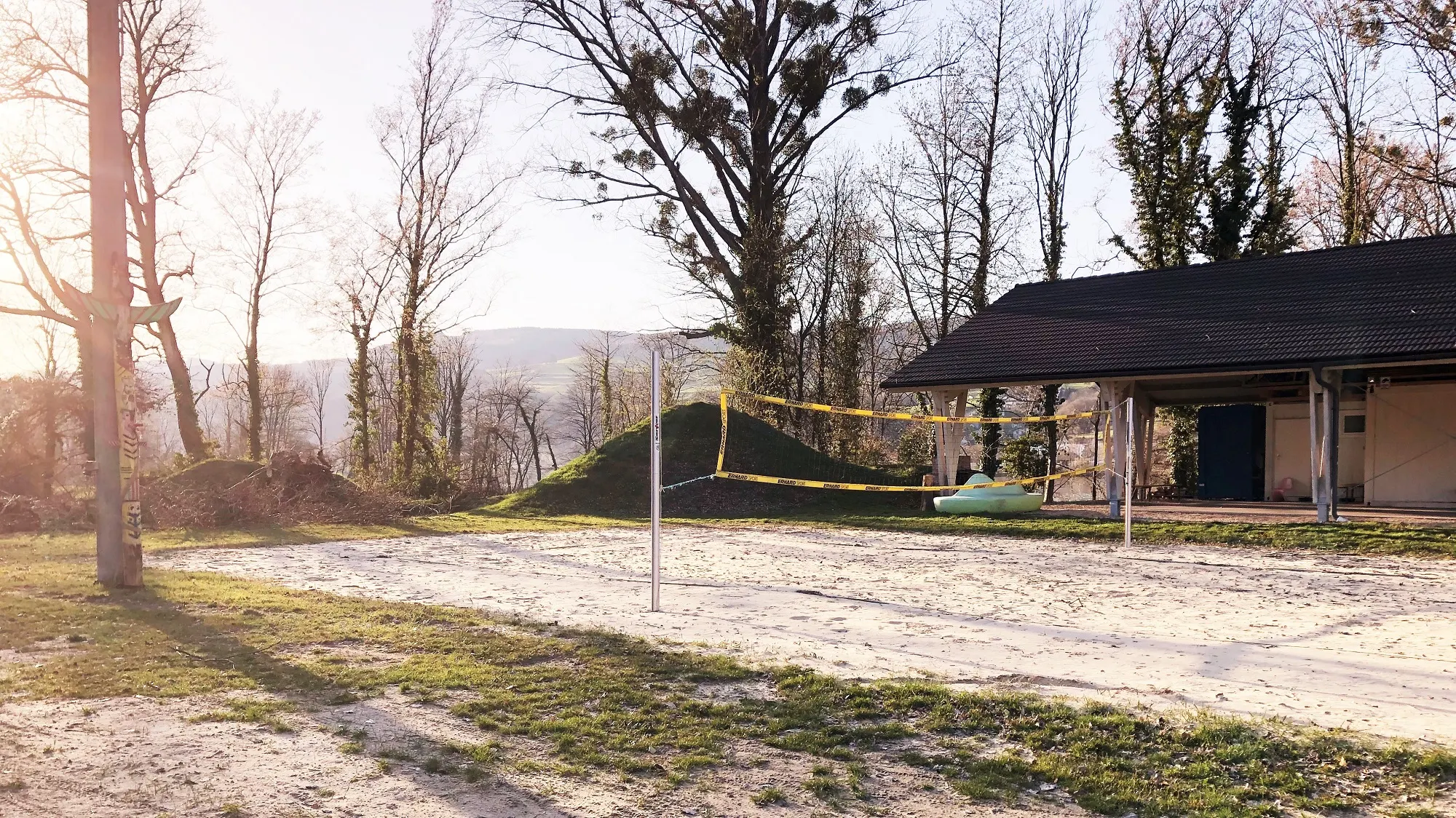Beachvolleyballplatz in Krummnussbaum mit Netz und Bäumen im Hintergrund.