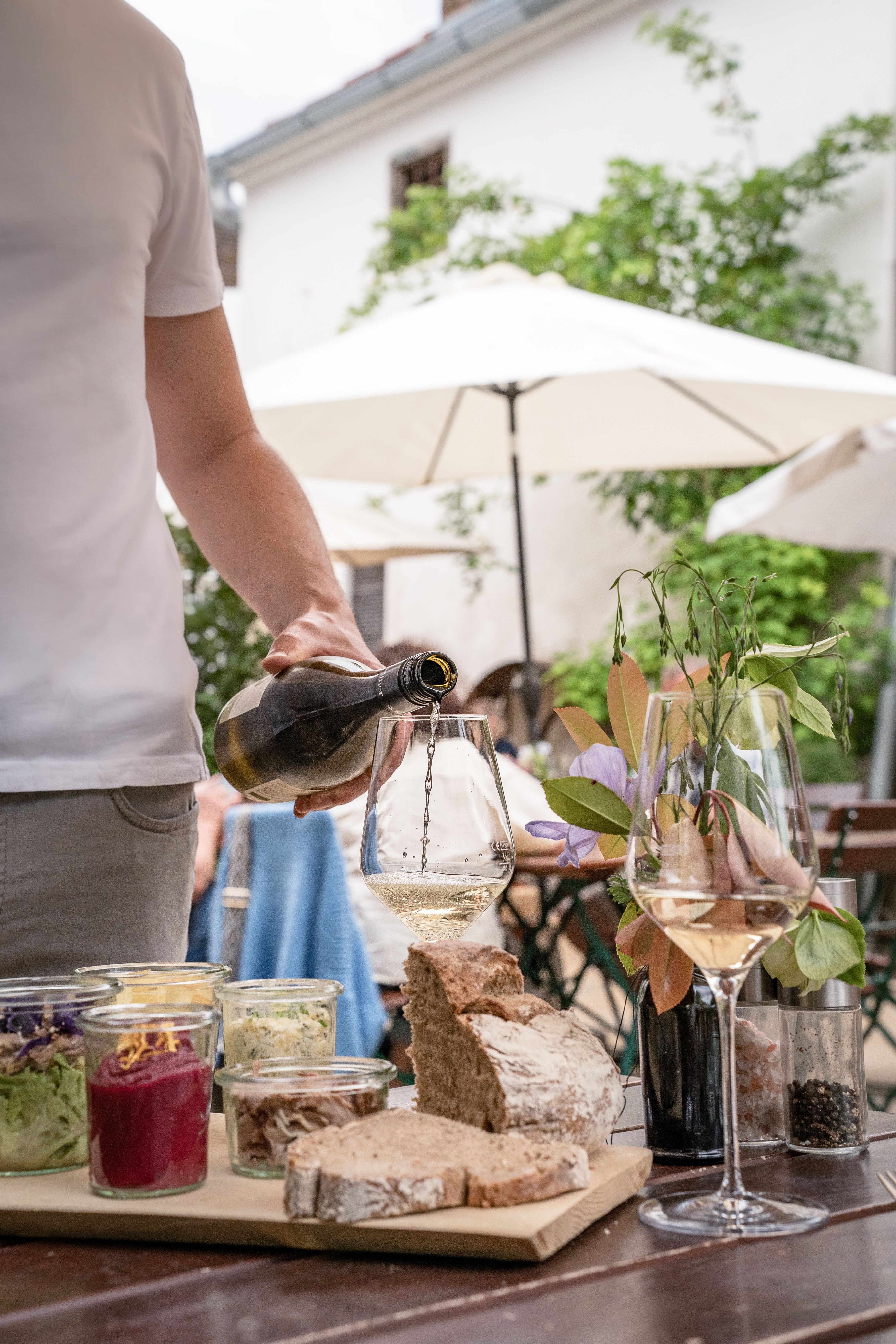 Winzer schenkt Wein ein. Heurigenjause in Gläsern gefüllt