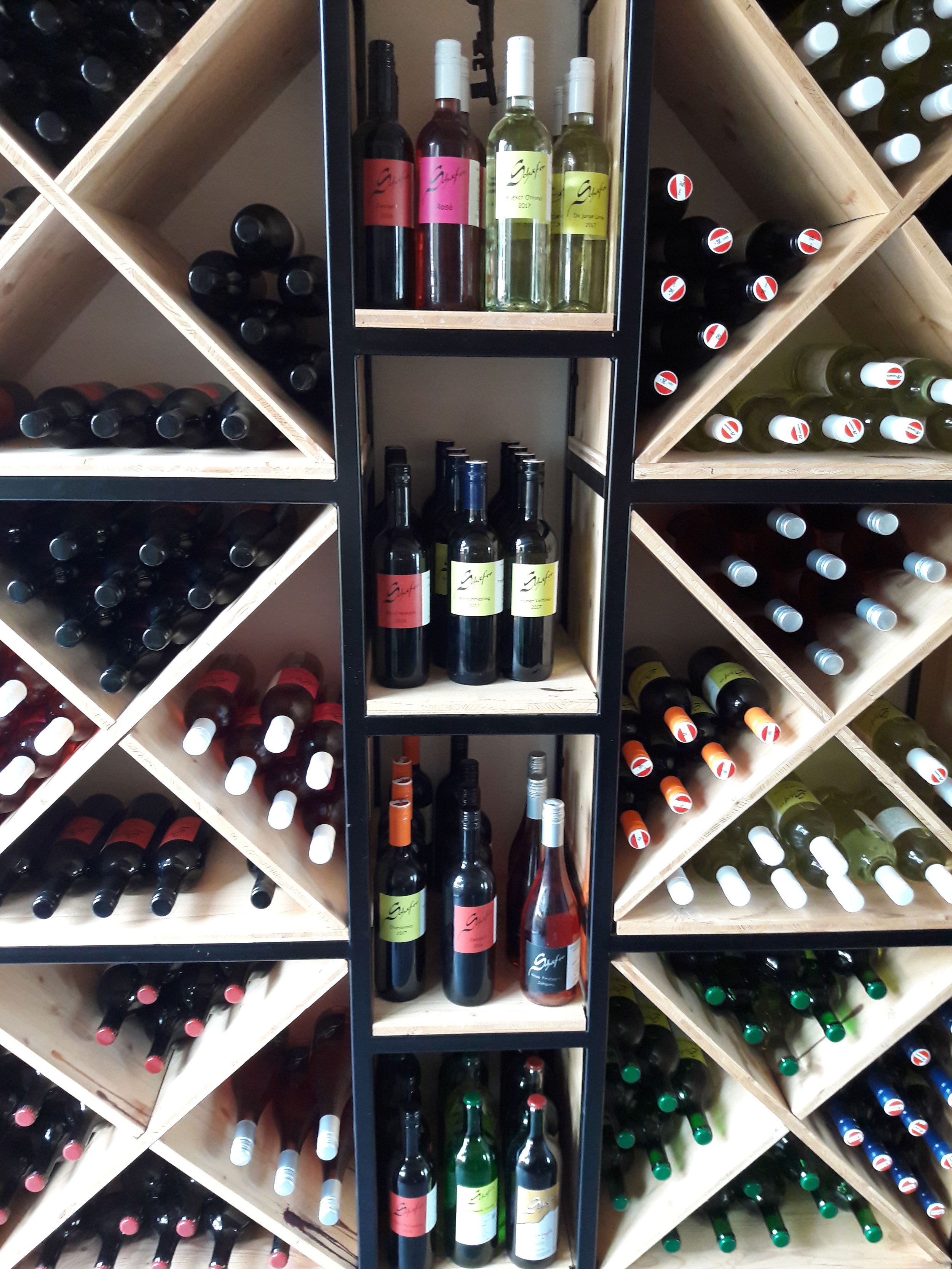 Weinflaschen in einem Holzregal mit diagonalen Fächern.
