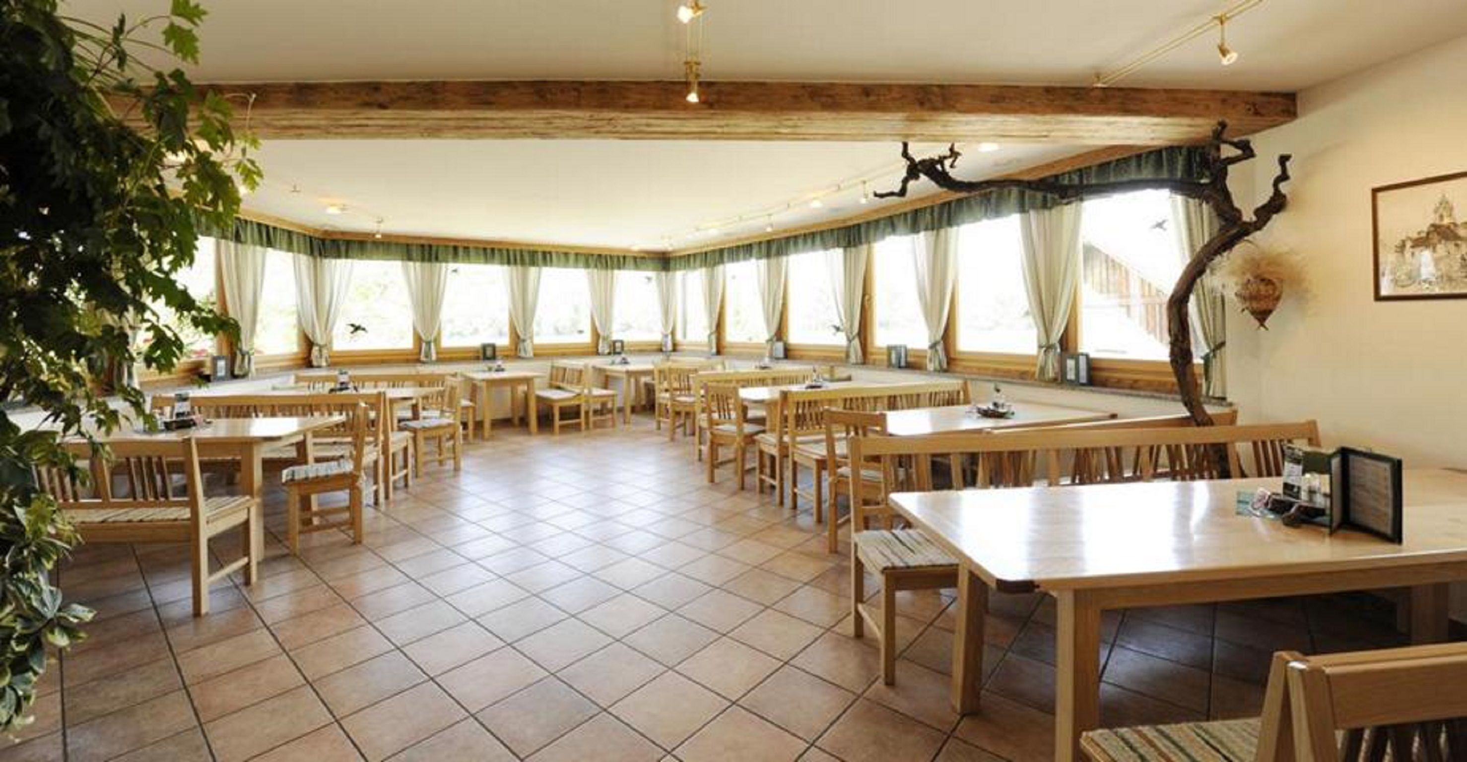 Innenansicht eines Heurigenlokals mit Holzmöbeln und großen Fenstern.