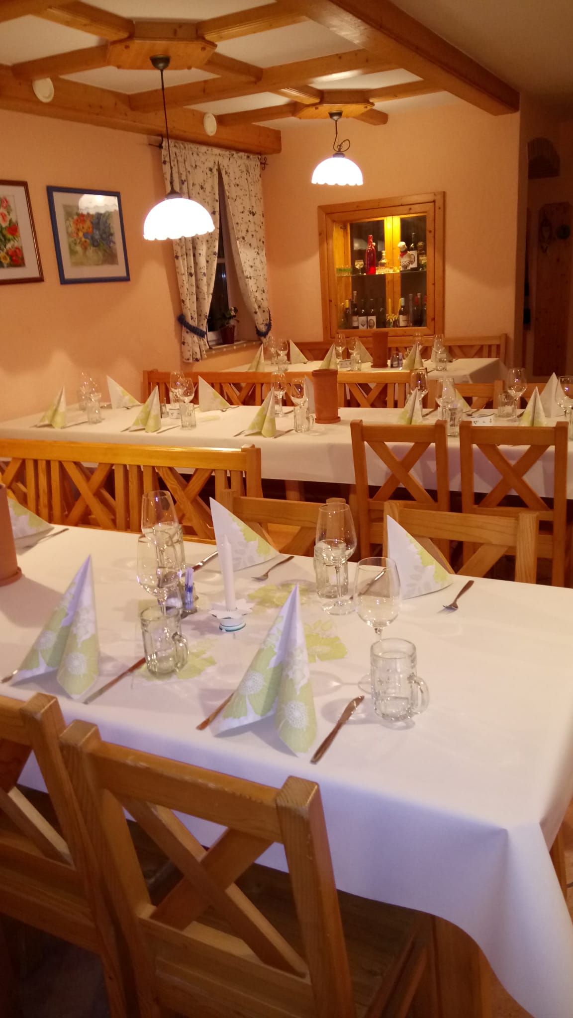 Eingedeckte Tische innen mit weißer Tischwäsche 