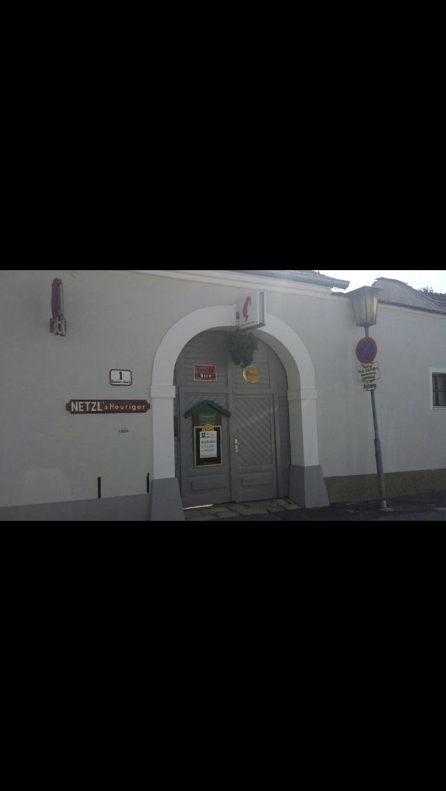 Eingang zu Netzl's Heuriger mit grauer Tür und Schild.
