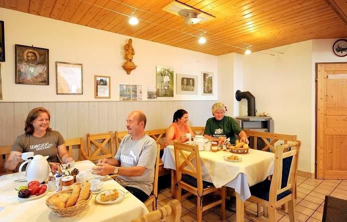 Menschen frühstücken in einem gemütlichen Raum mit Holzmöbeln und Dekorationen an der Wand.