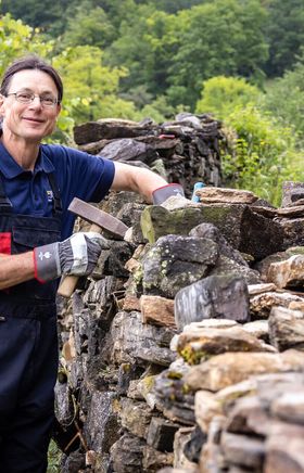 Eine Frau beim Bau einer Trockensteinmauer