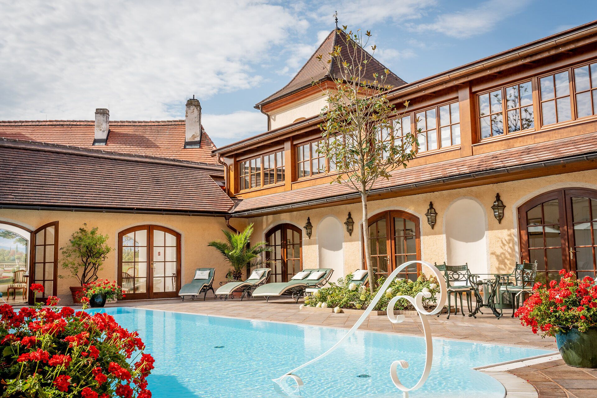 Die malerische Kulisse des Schlosses Dürnstein, umgeben von blühenden roten Geranien und dem glitzernden Wasser des Pools, lädt zum Entspannen und Verweilen ein. Hier, wo die Natur auf historische Architektur trifft, können Besucher die Schönheit der Umgebung in vollen Zügen genießen.