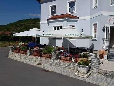 Außenansicht eines Gebäudes mit Terrasse und Sonnenschirmen.