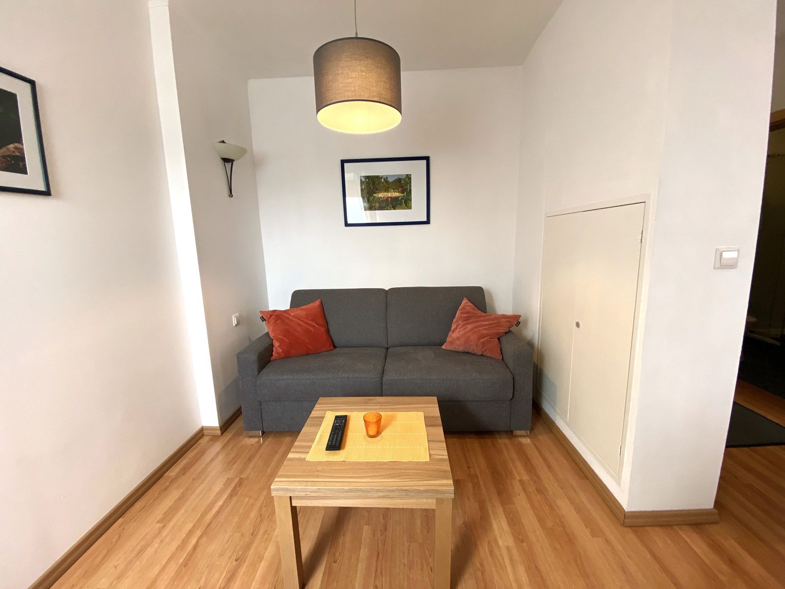 Wohnzimmer mit grauem Sofa, Holztisch und Wandbildern.