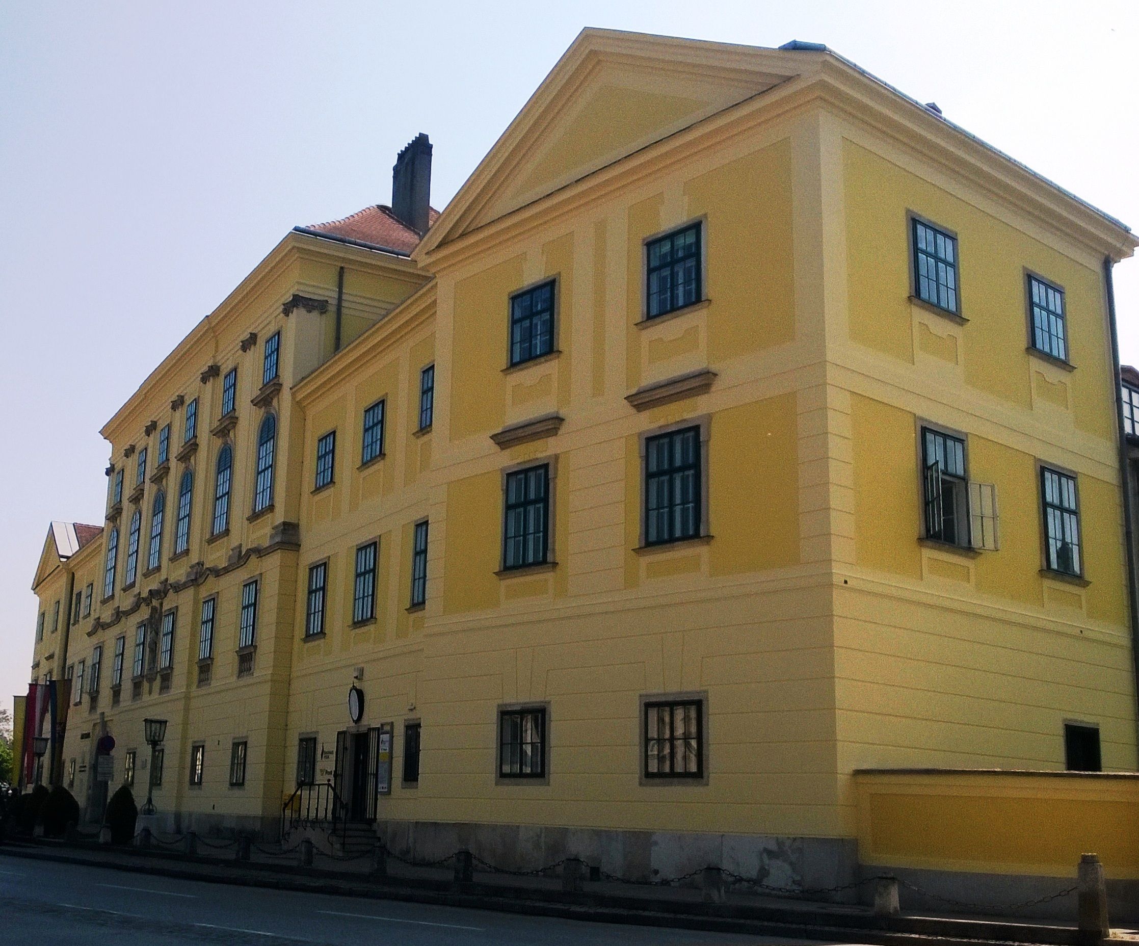 Gelbes historisches Gebäude mit vielen Fenstern und einem Giebeldach.