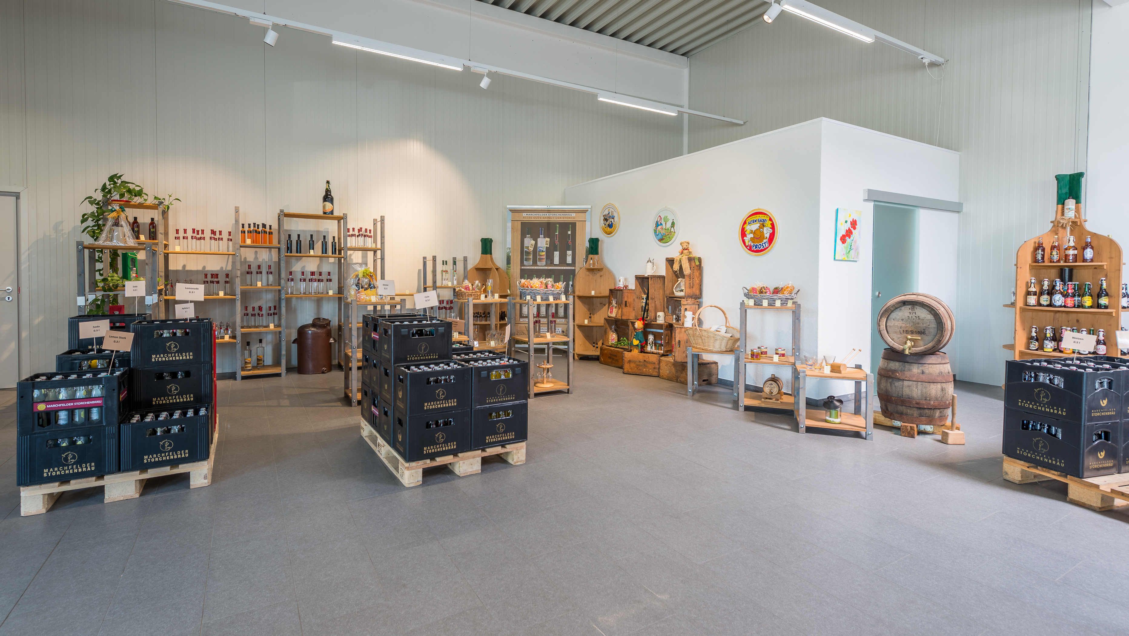 Interior view of a store with crates of drinks, shelves full of bottles and decorations.