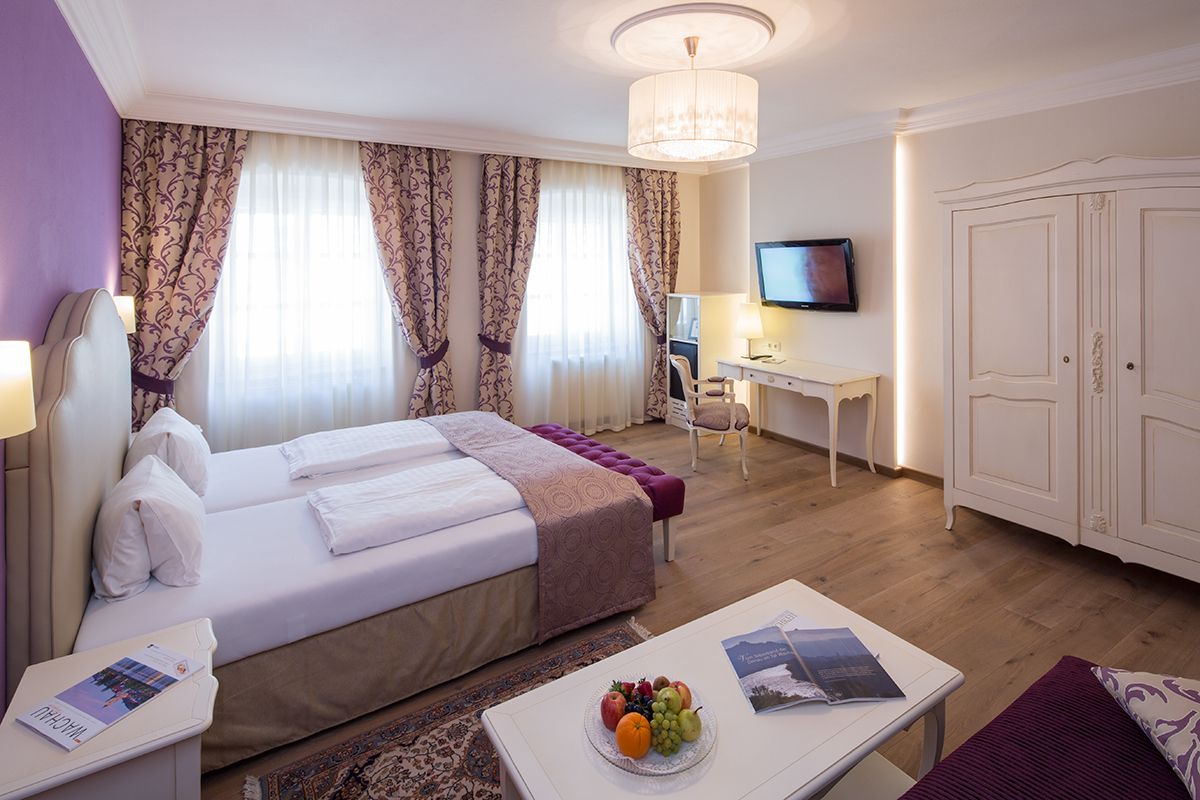 Elegantes Hotelzimmer mit Doppelbett, Schreibtisch, TV und Obstteller.