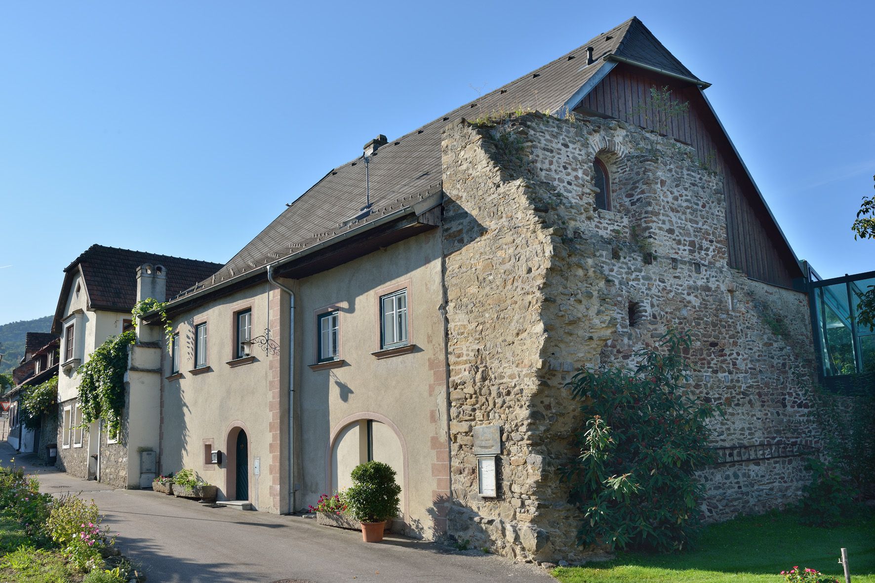 Historisches Gebäude mit Steinmauer und modernem Anbau.