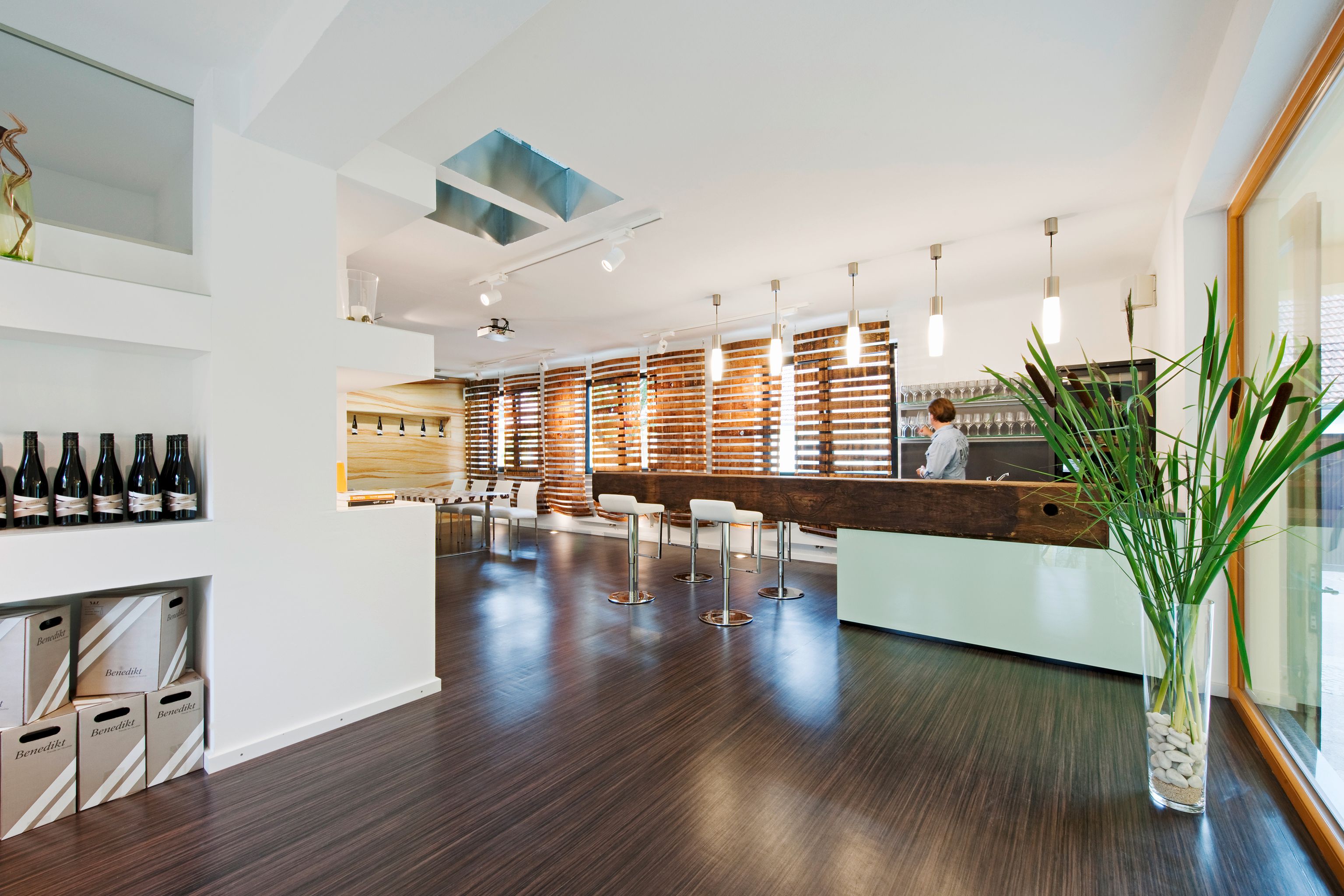 Moderner Verkostungsraum mit Bar, Stühlen und Weinflaschen.