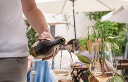 Winzer schenkt Wein ein. Heurigenjause in Gläsern gefüllt