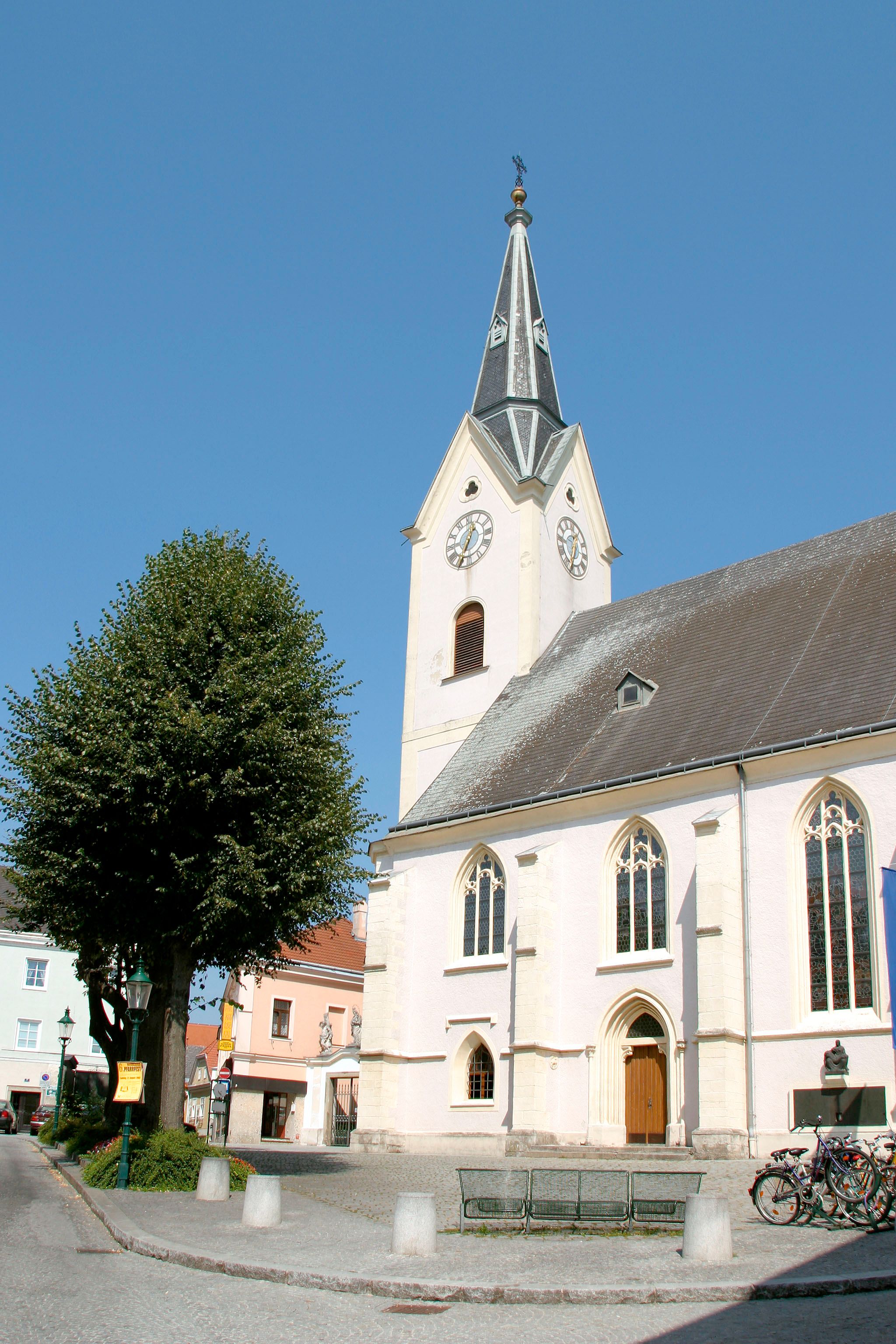 Stadtpfarrkirche St. Laurenz mit Turm und Uhr vor blauem Himmel.