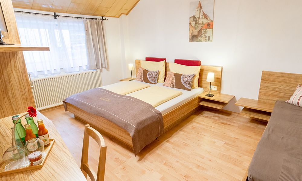 Gemütliches Gästezimmer mit Doppelbett, Holzmöbeln und Dekoration.