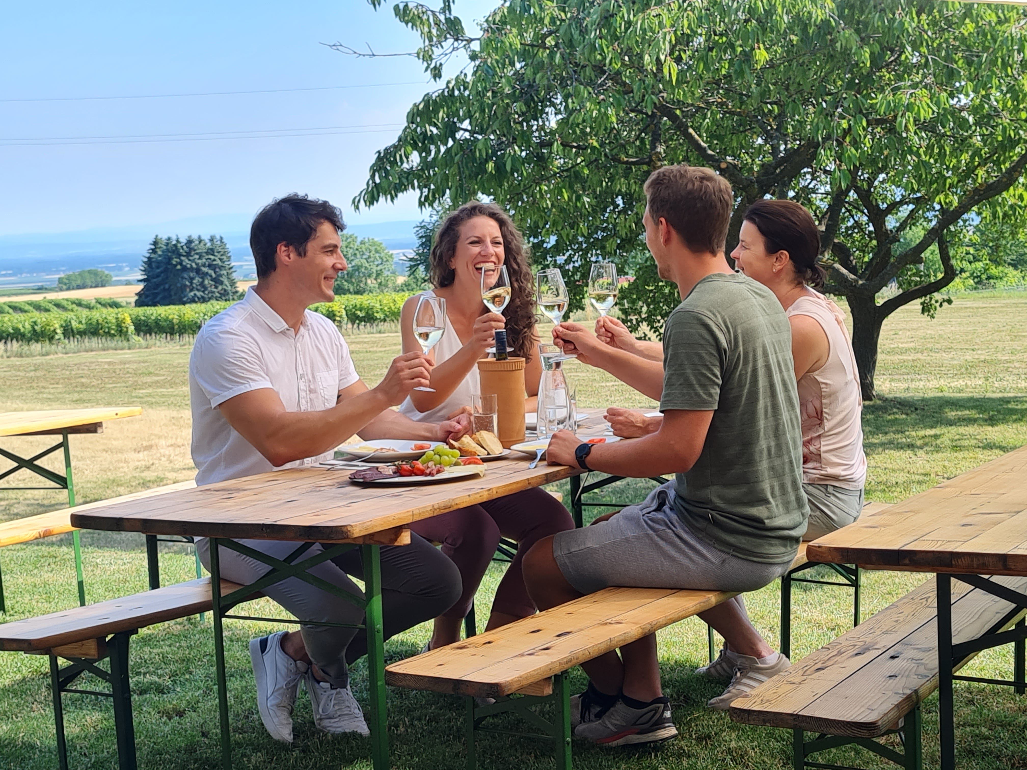 4 Personen am Heurigentisch, die sich zuprosten