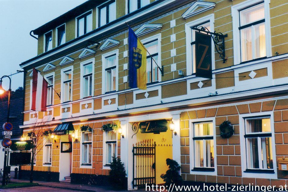 Außenansicht des Hotels Zierlinger mit gelber Fassade und Flaggen.