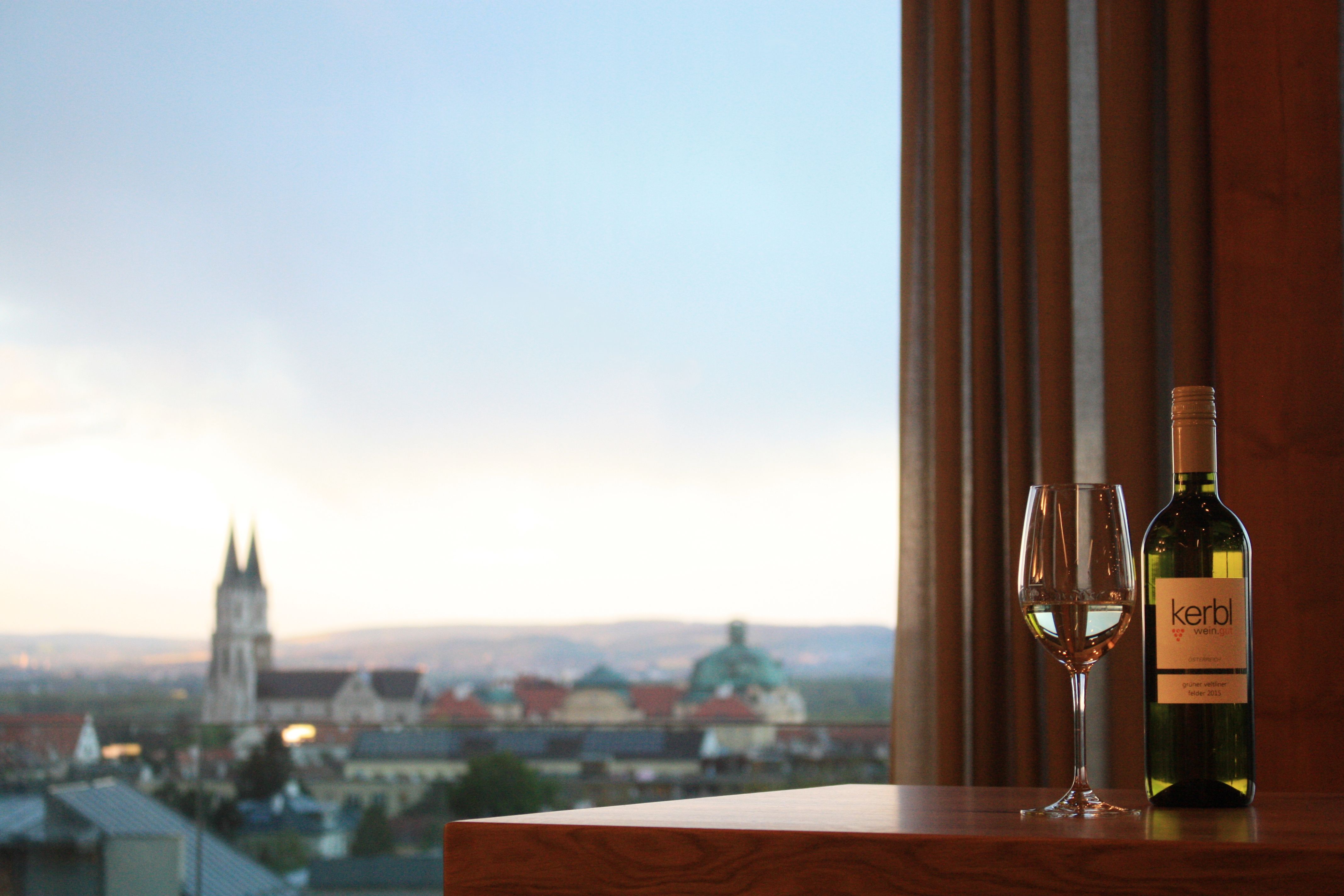 Weinflasche und Glas vor Stadtpanorama mit Kirche.