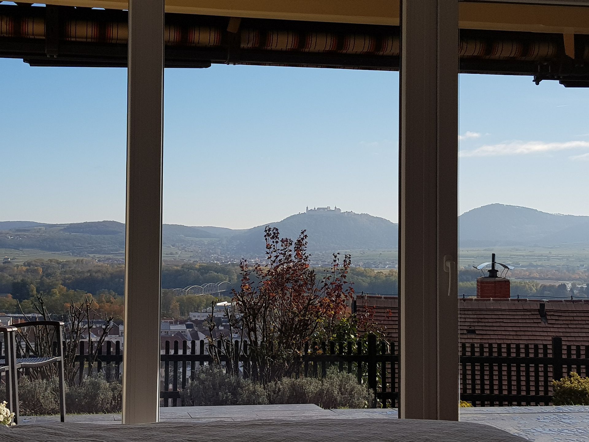 Blick aus einem Fenster auf eine hügelige Landschaft mit einem Kloster auf einem Hügel im Hintergrund.