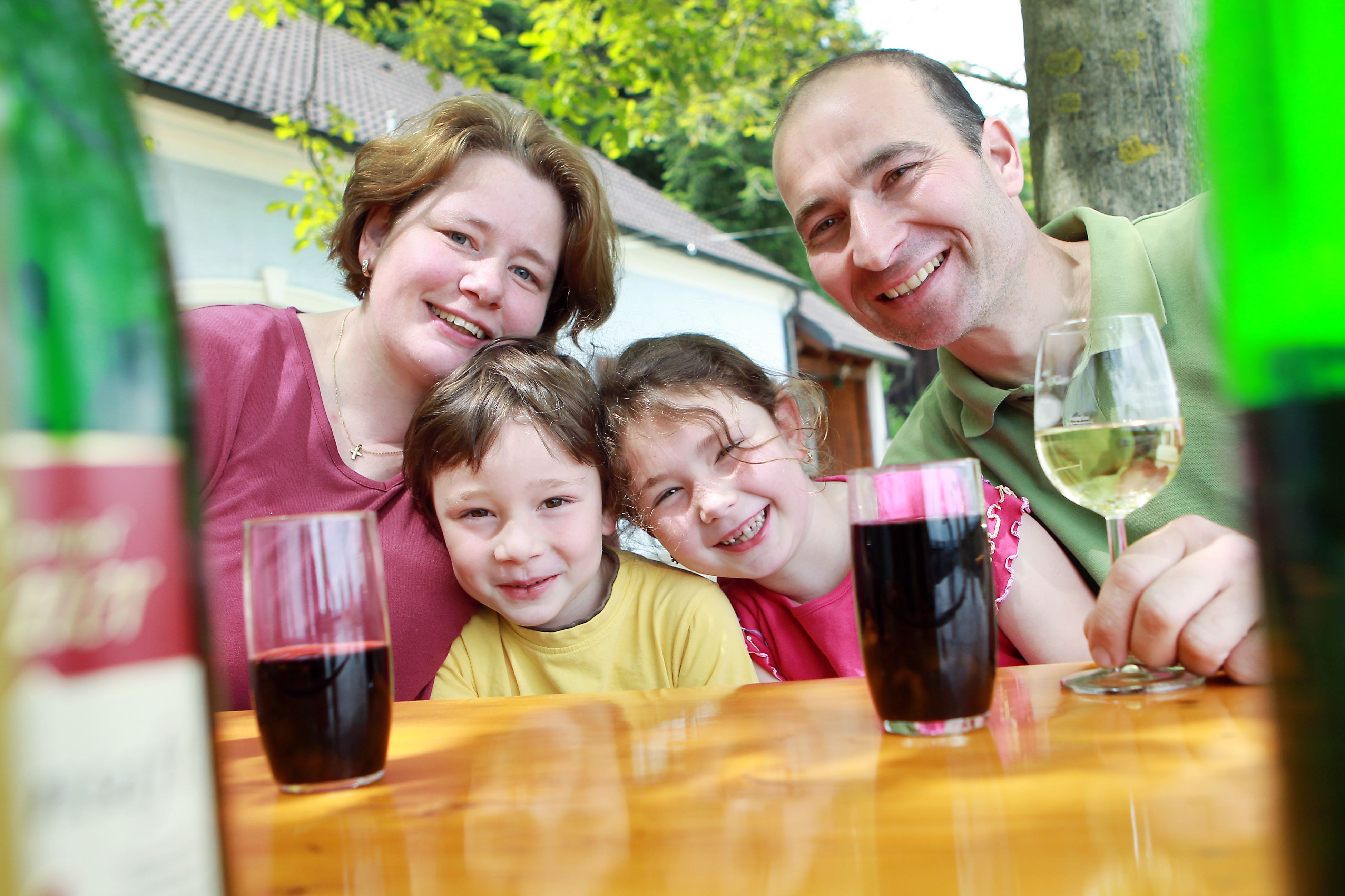 Family sitting at an outdoor table and smiling at the camera.