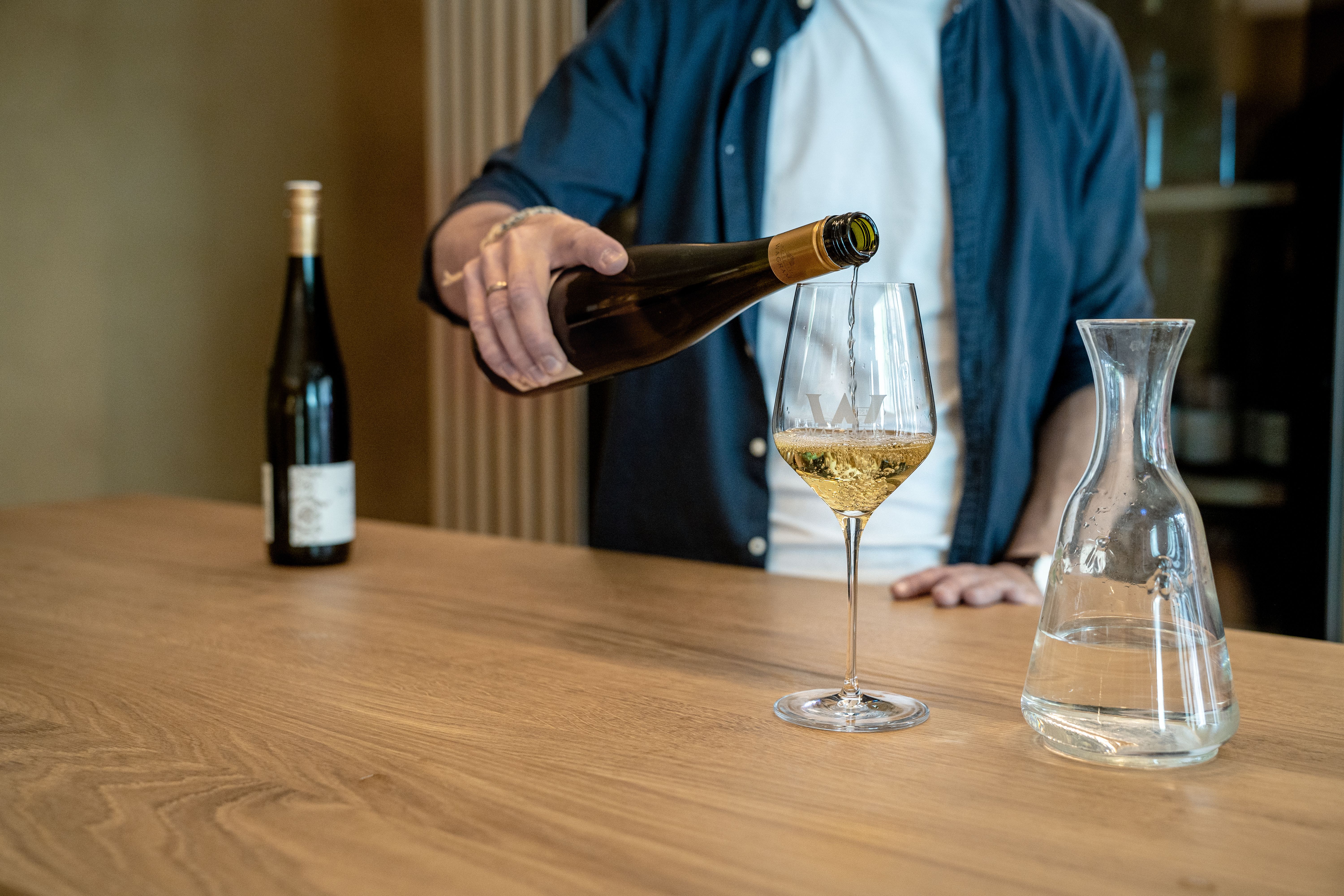 Mann schenkt Glas Wein ein