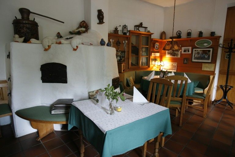 Gemütliches Wirtshaus mit rustikaler Einrichtung, Holzmöbeln und Kachelofen.