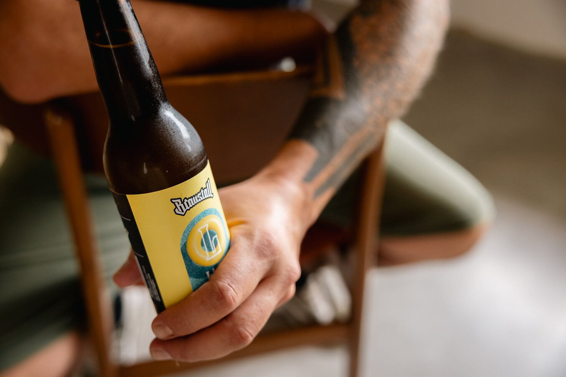 Hand hält eine Braustall-Bierflasche.