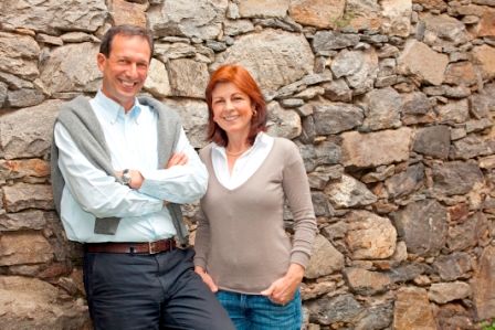 Ein Mann und eine Frau stehen lächelnd vor einer Steinmauer.