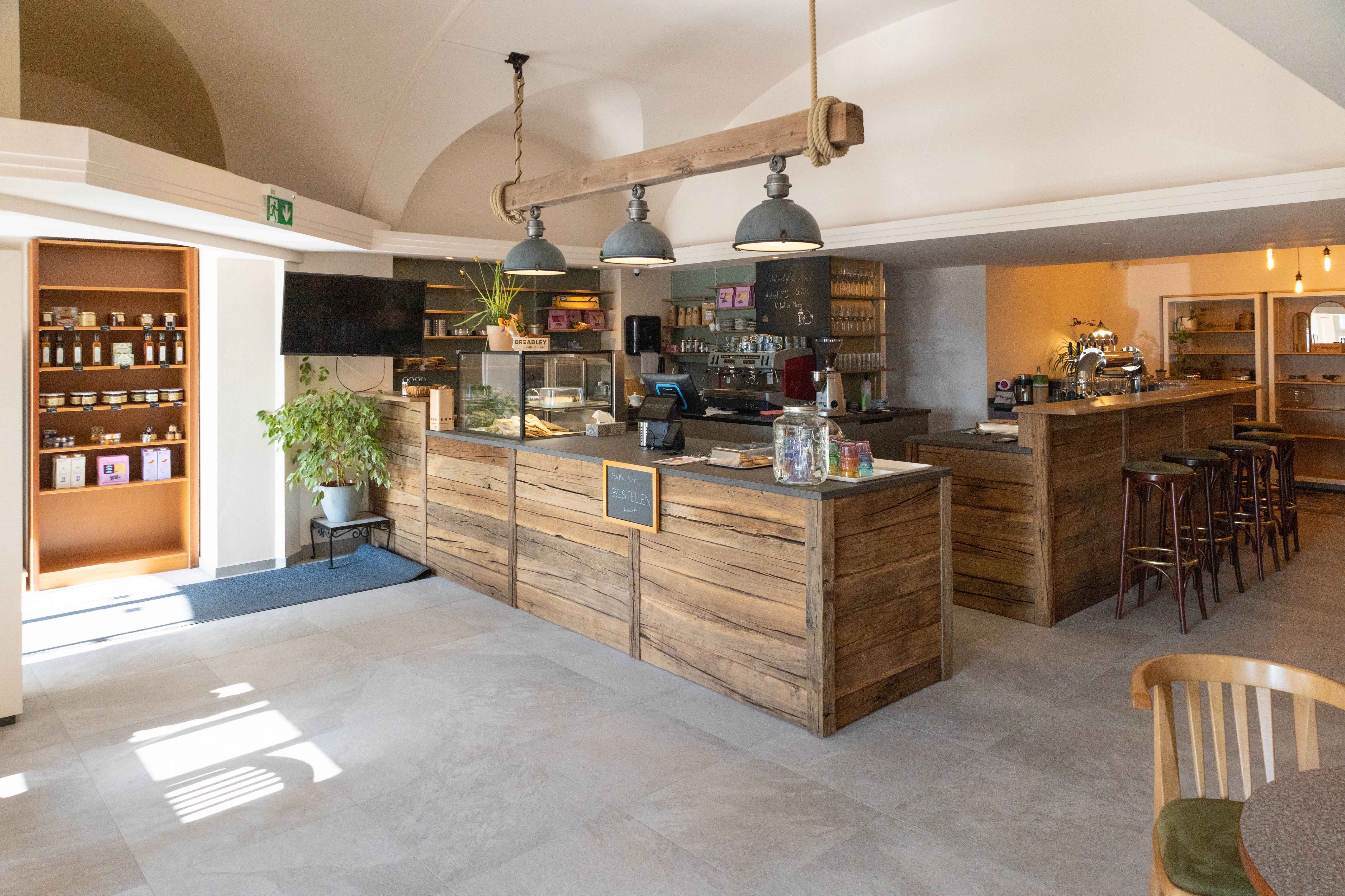 Innenansicht eines gemütlichen Cafés mit Holzmöbeln und Theke.