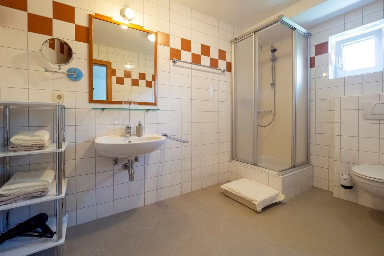 Modernes Badezimmer mit Dusche, Waschbecken und Handtuchregal.