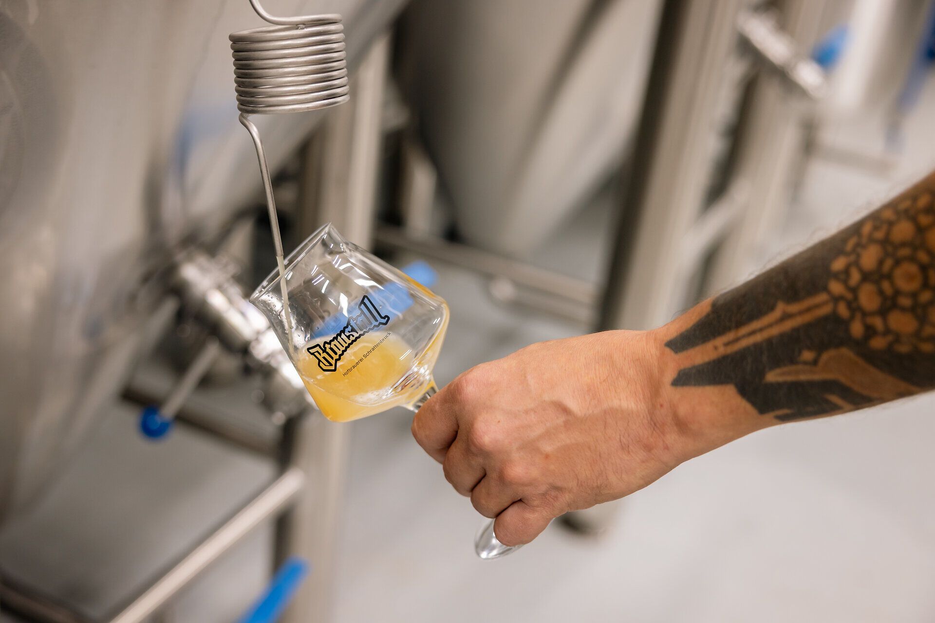 Glas mit hellem Bier und Braustall-Logo.