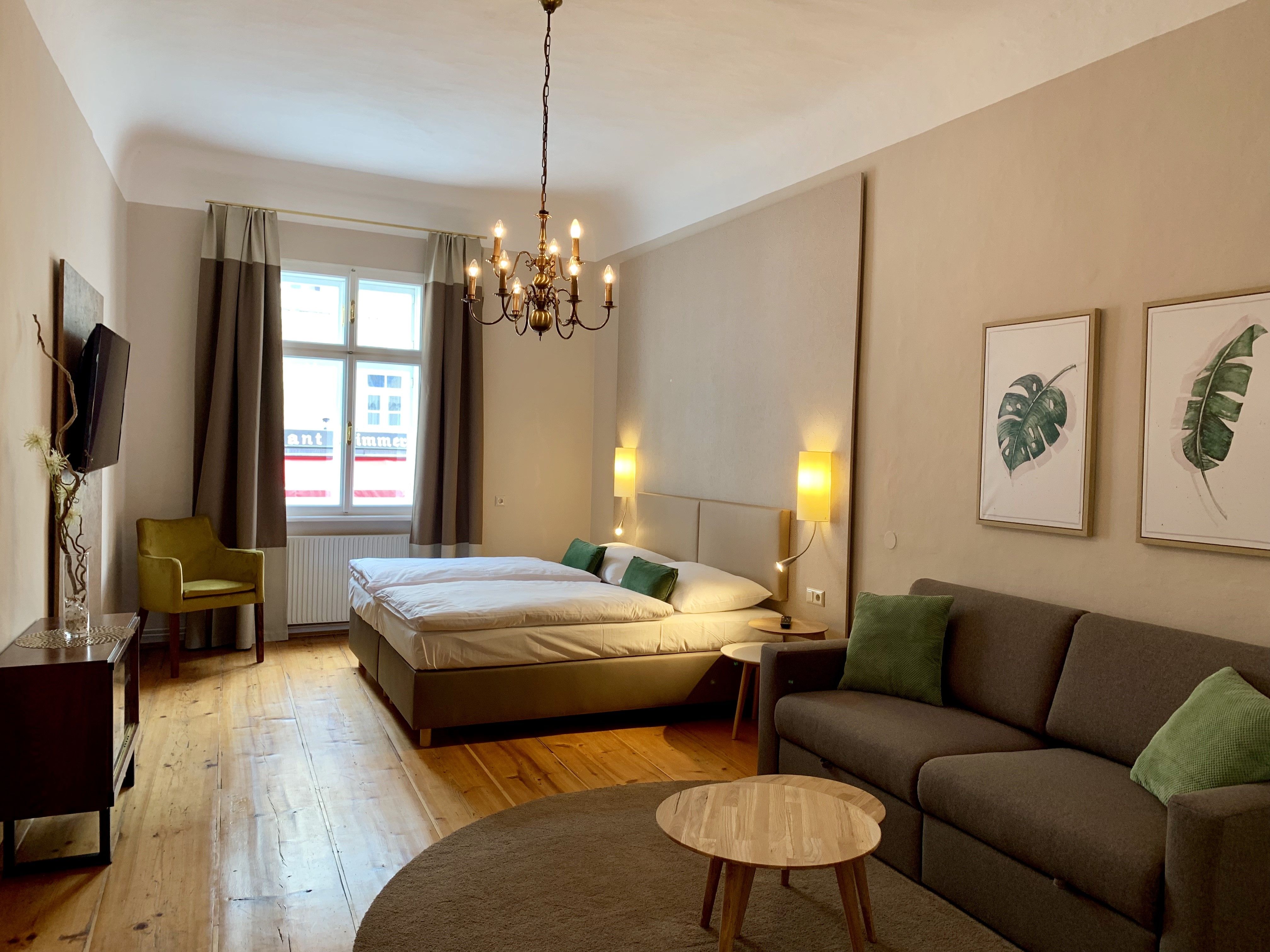 Gemütliches Schlafzimmer mit Doppelbett, Sofa, Sessel und TV.