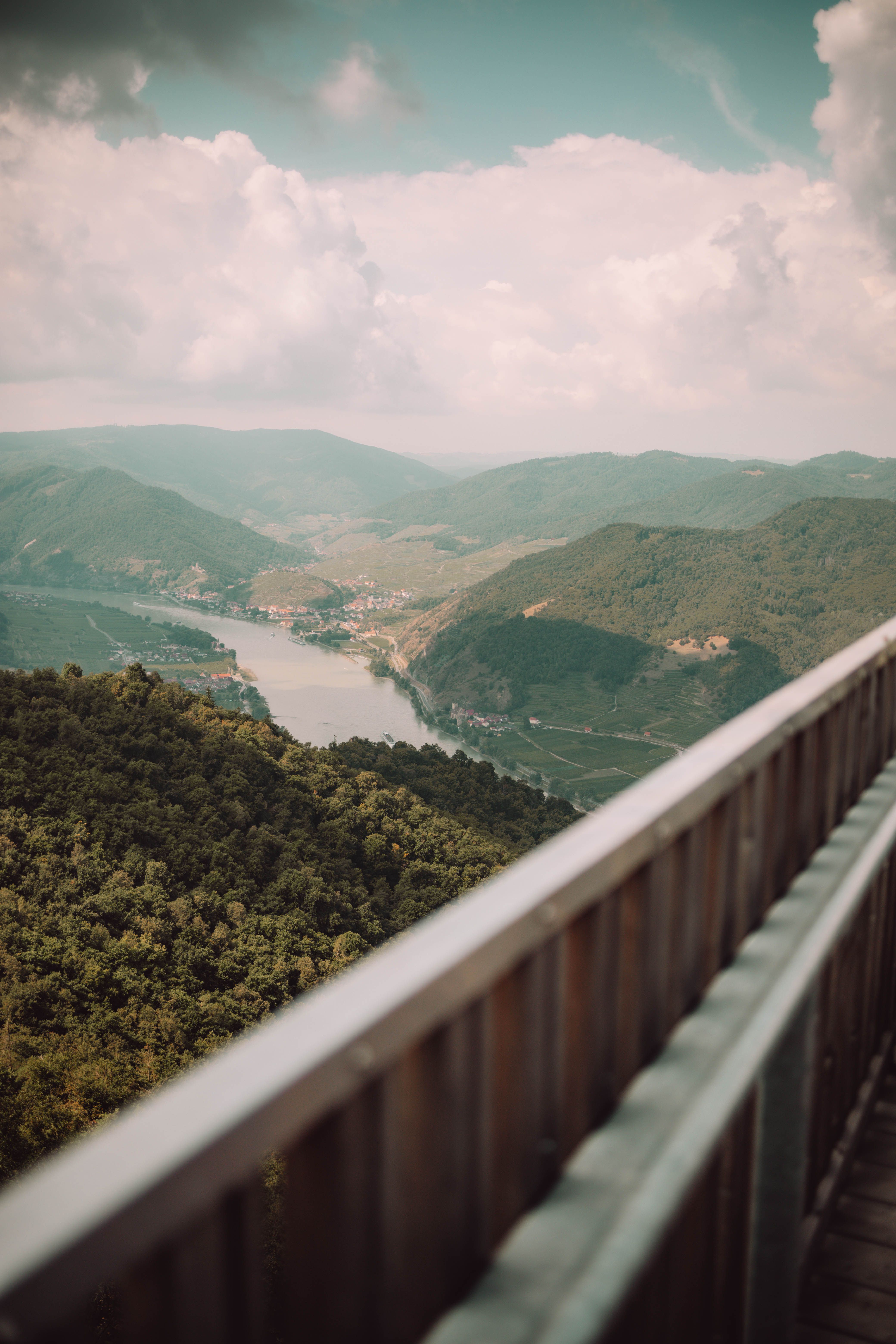 Aussichtsplattform mit Blick auf Fluss und Weinberge in einer grünen Landschaft.