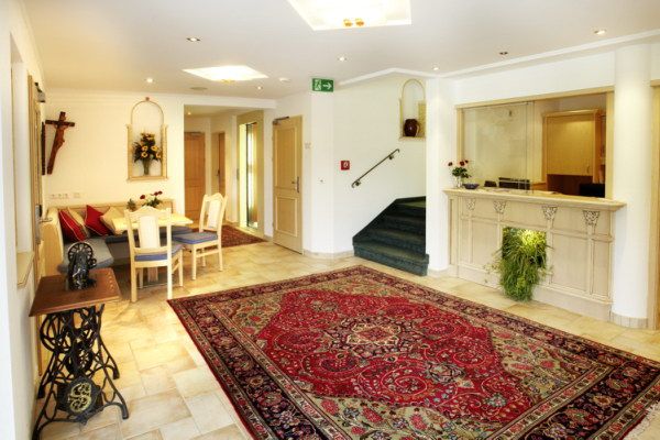 Elegáns recepció szőnyeggel, recepciós pult és ülősarok.