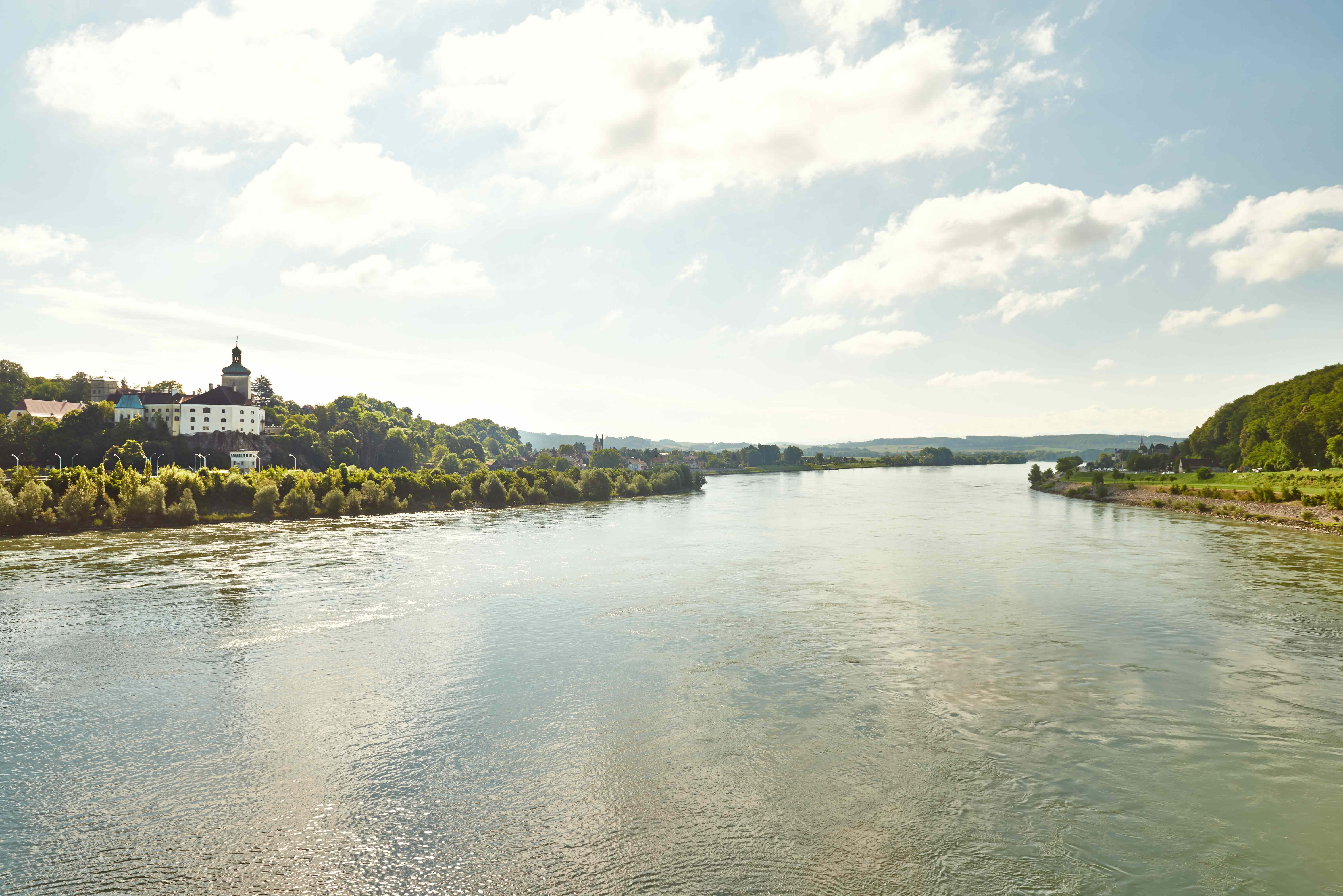Flusslandschaft mit Gebäuden am Ufer und bewölktem Himmel.