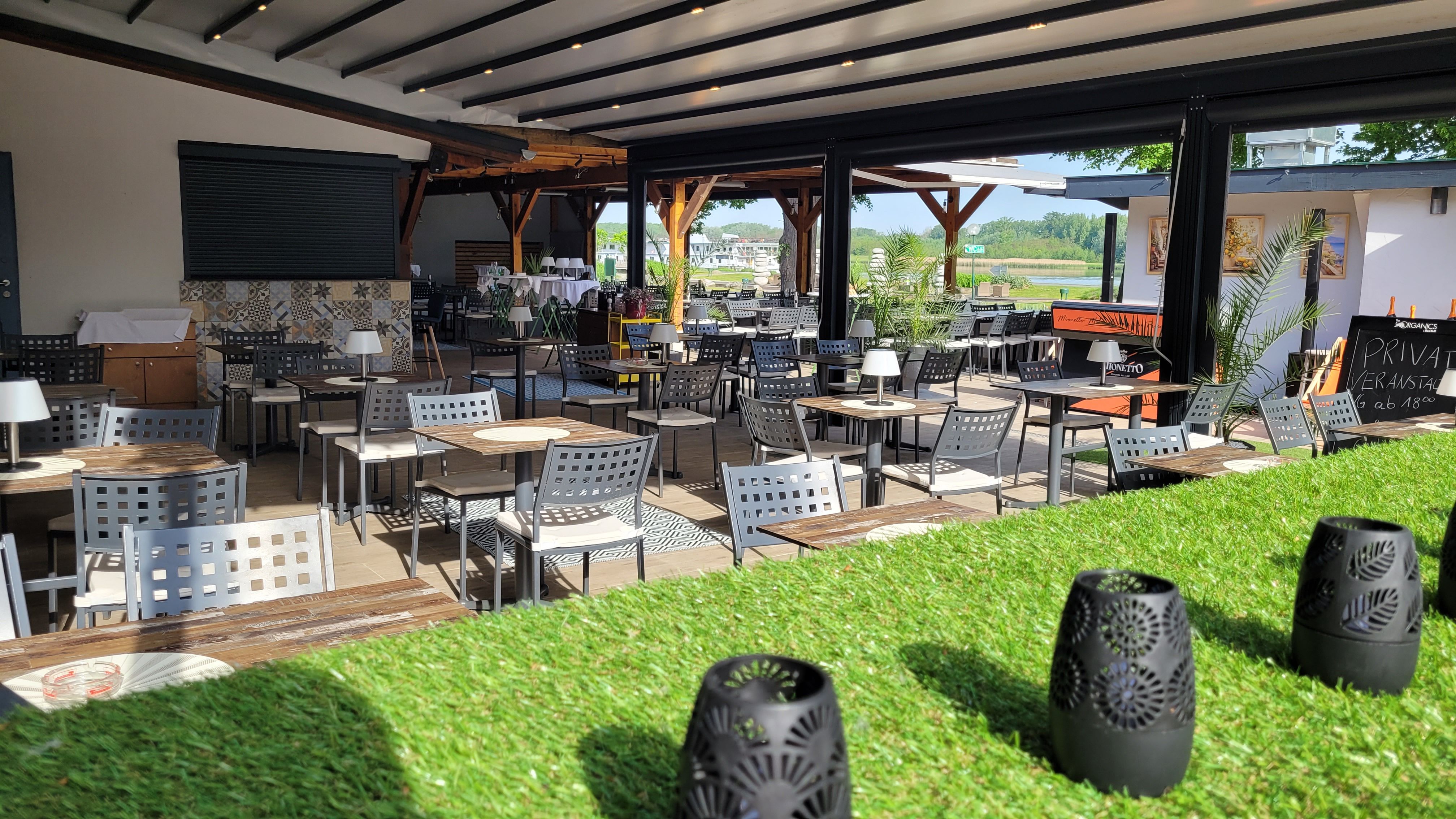 Gastgarten mit Stühlen und Tischen mit Blick auf die Donau 
