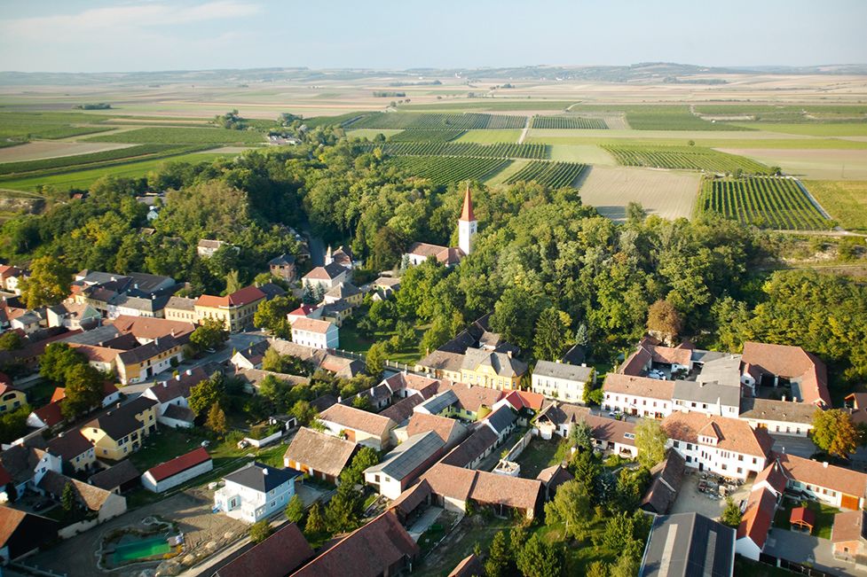 Luftaufnahme eines Dorfes mit Kirche und umliegenden Feldern.