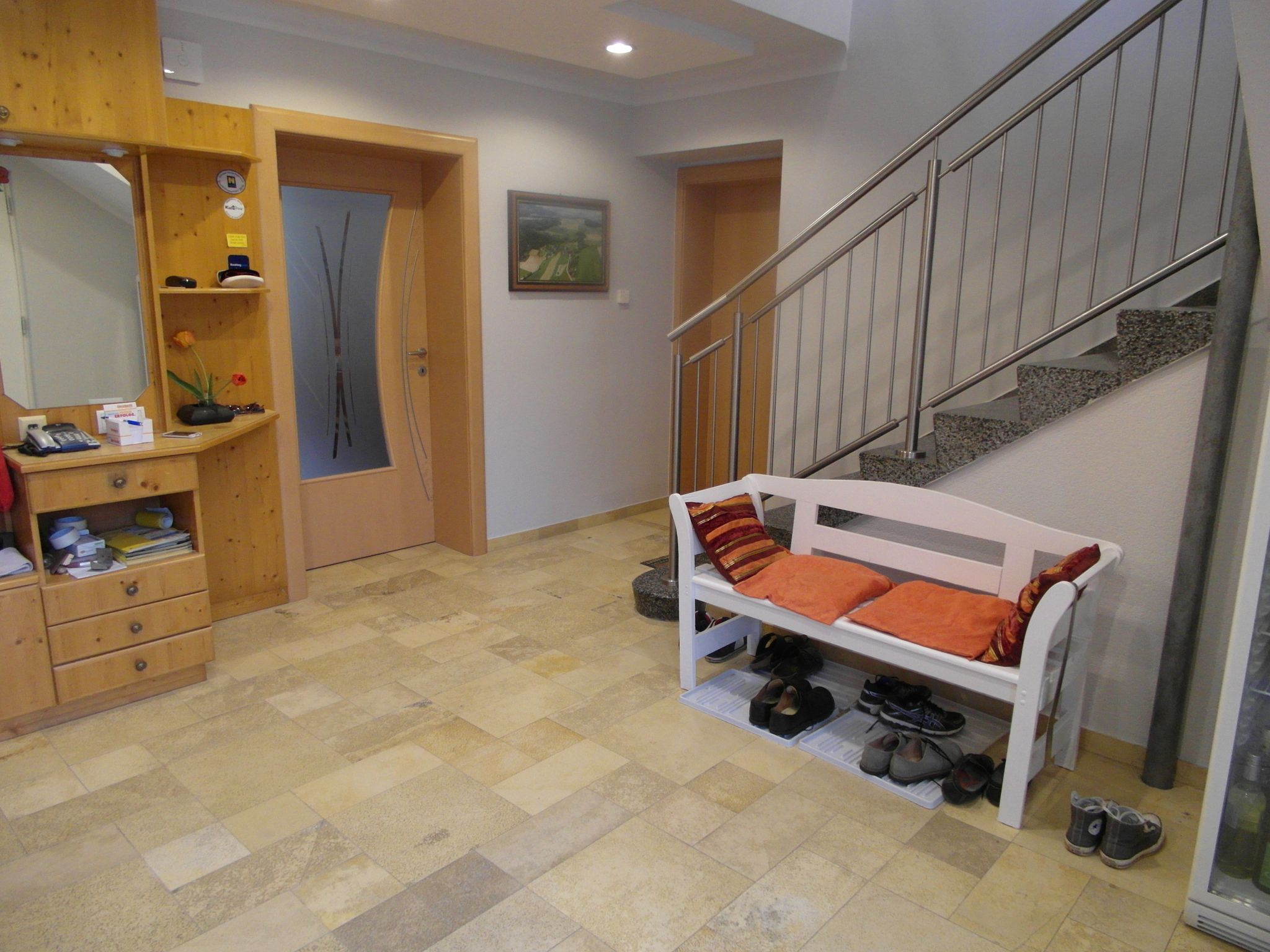 Eingangsbereich mit Holzkommode, Bank mit Kissen und Treppe.