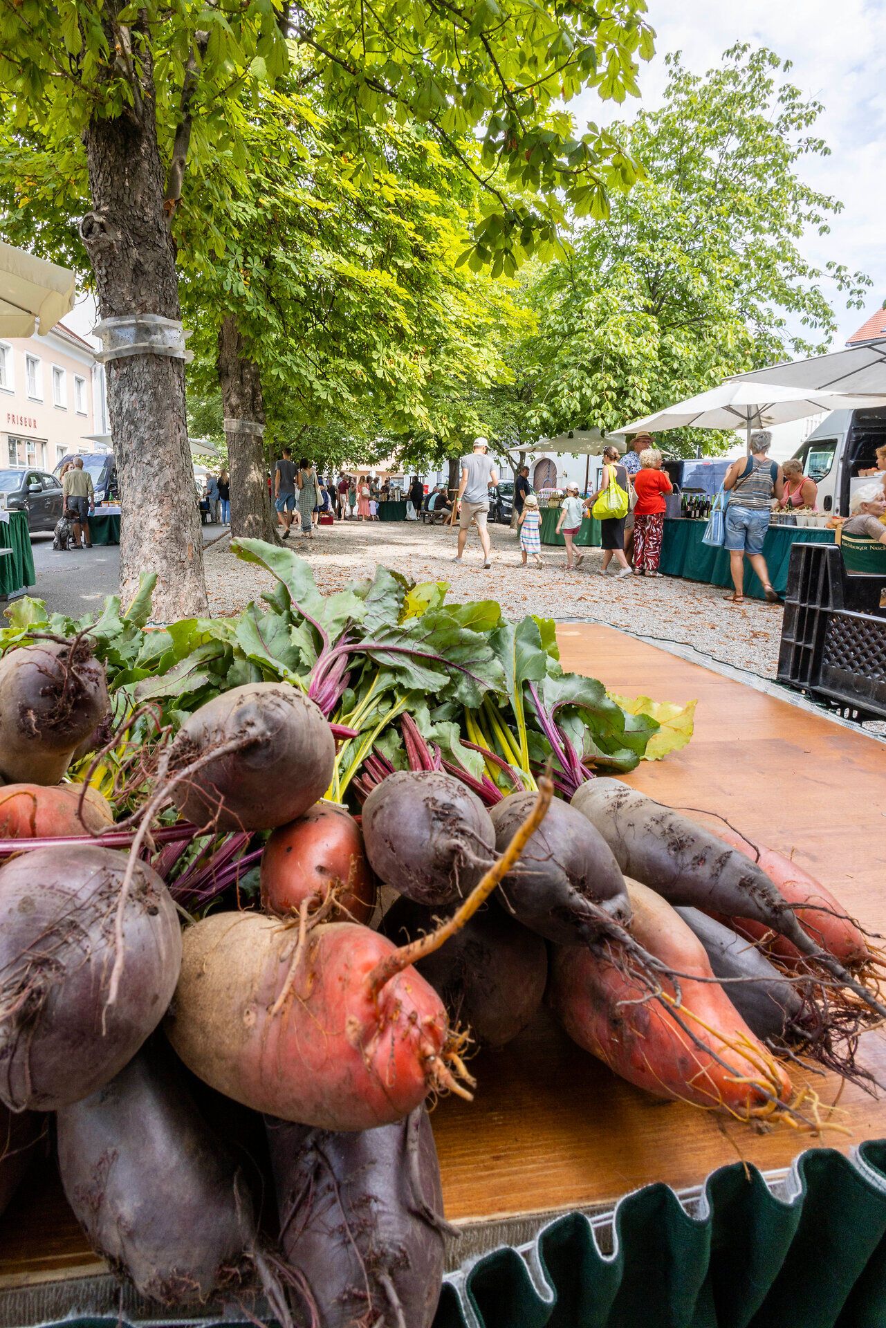 Frisch geerntete Rote Rüben mit Erde und Blättern auf einem Tisch.