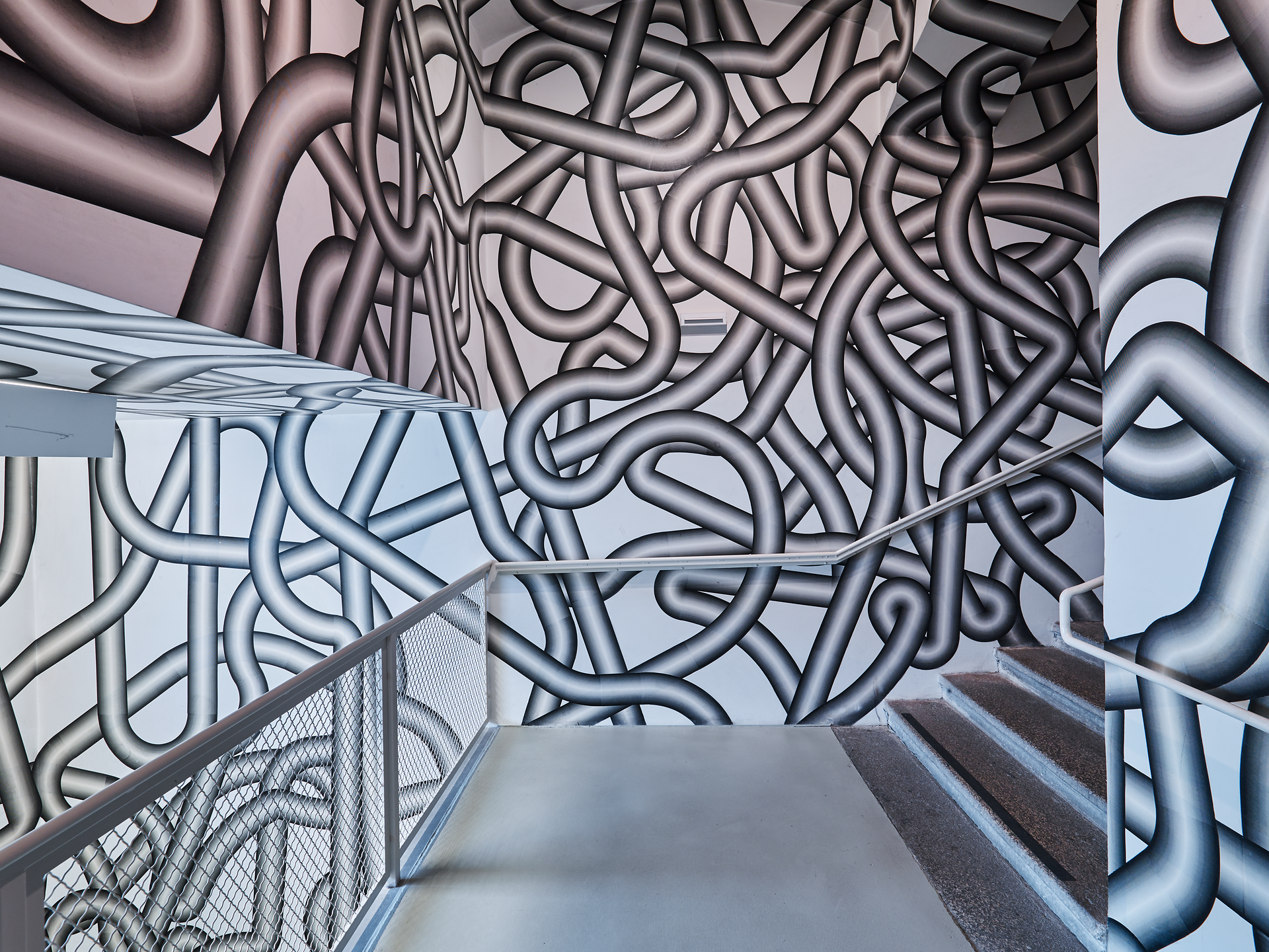 Die dynamischen, verschlungenen Linien der Wandgestaltung verleihen dem Raum eine lebendige Energie. Hier wird Kunst zu einem Erlebnis, das die Sinne anregt und zum Verweilen einlädt. Ein Ort, an dem Kreativität und Inspiration in der Luft liegen.