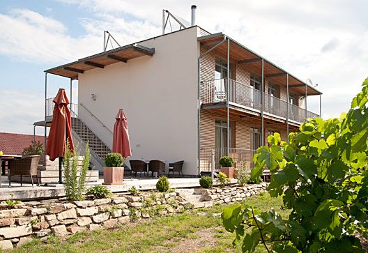 Modernes Gebäude mit Terrasse und Garten im Vordergrund.